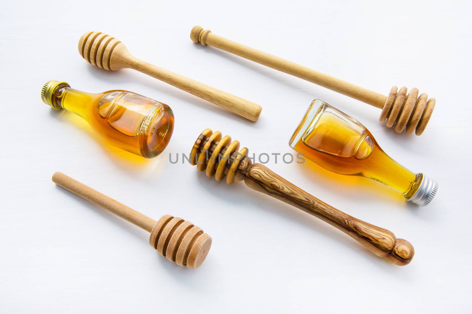 Honey wooden dipper and little honey bottle on white wooden back by Bowonpat