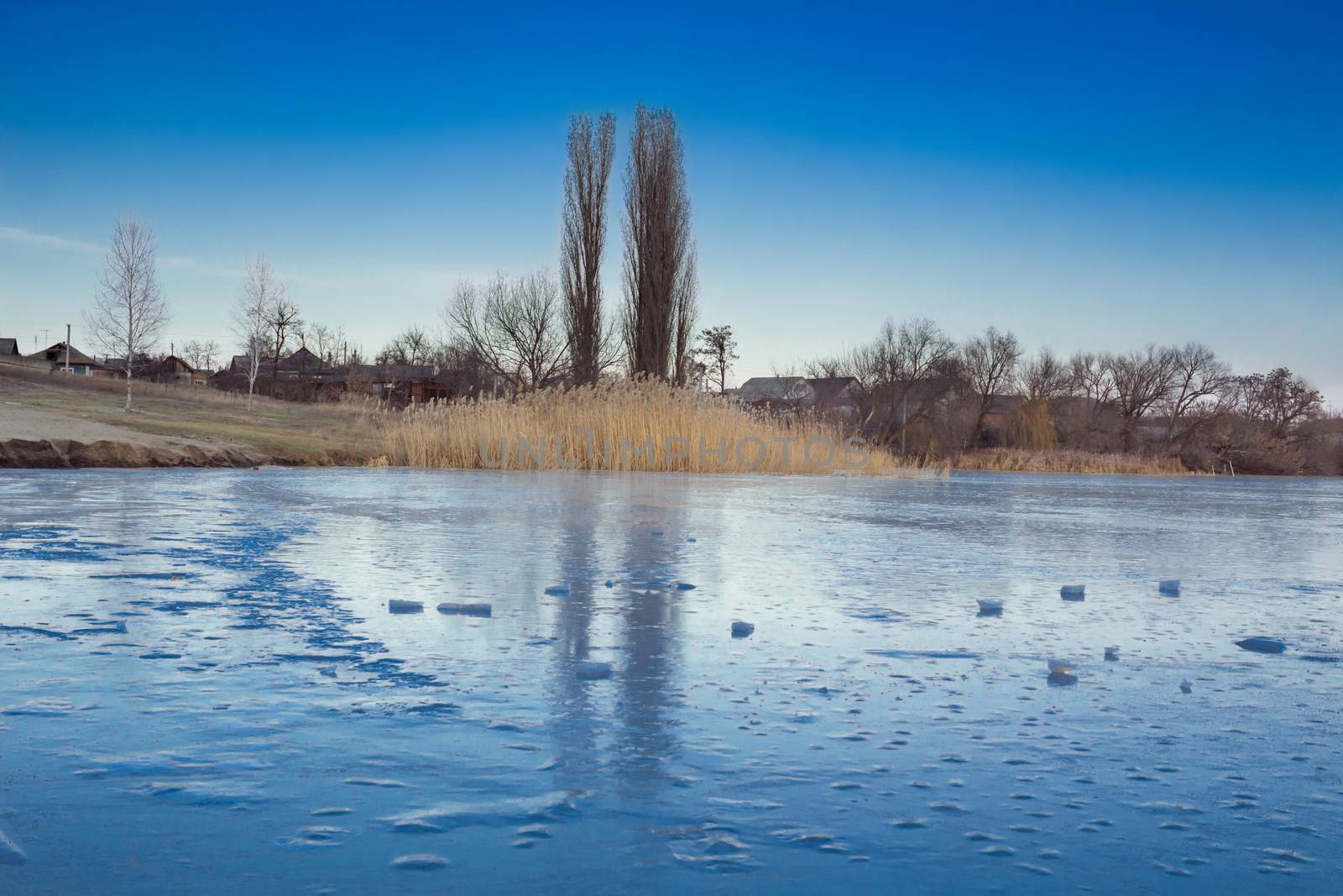 Winter paysage landscape of frozen village on iced lake river under snow