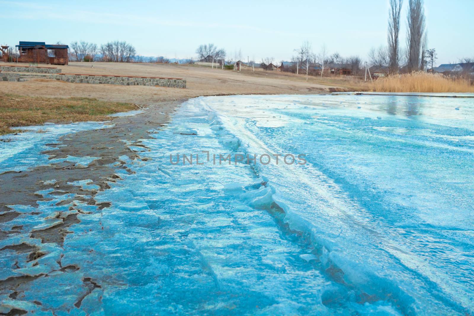 Blue iced frozen lake river on winter cold sandy beach
