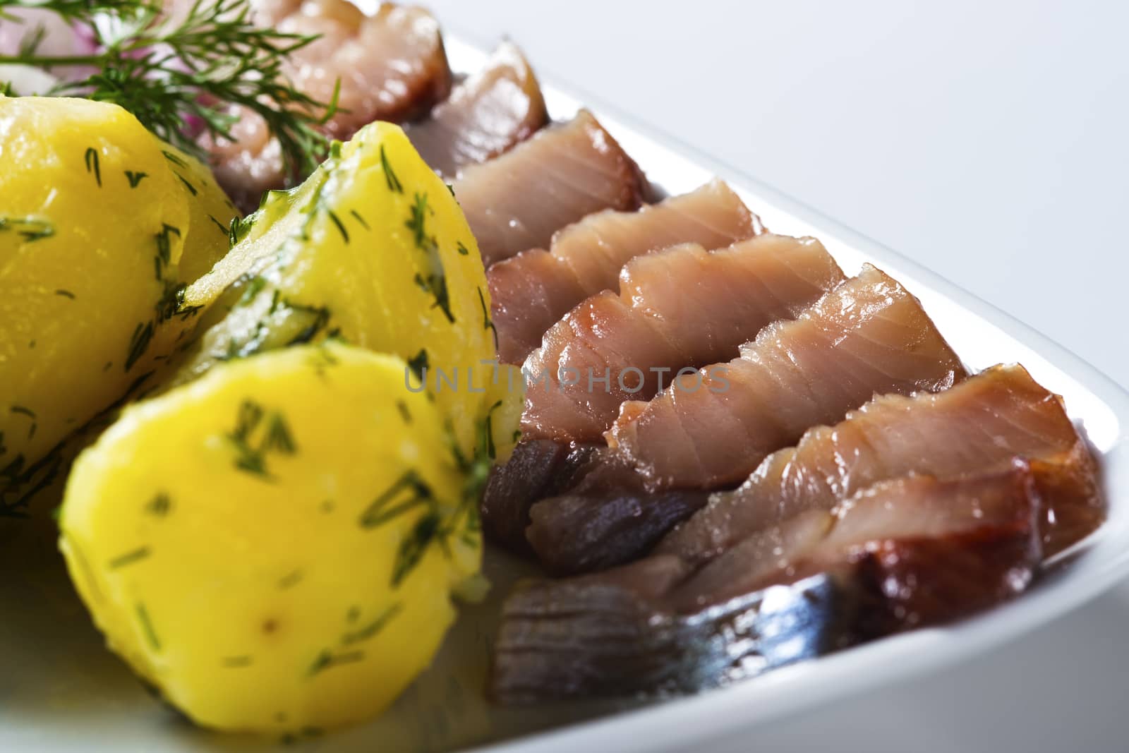 Herring fish slices with potatoes on the plate