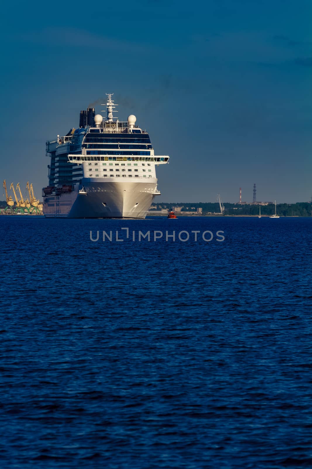 Giant white passenger ship moving past the port on a clear day