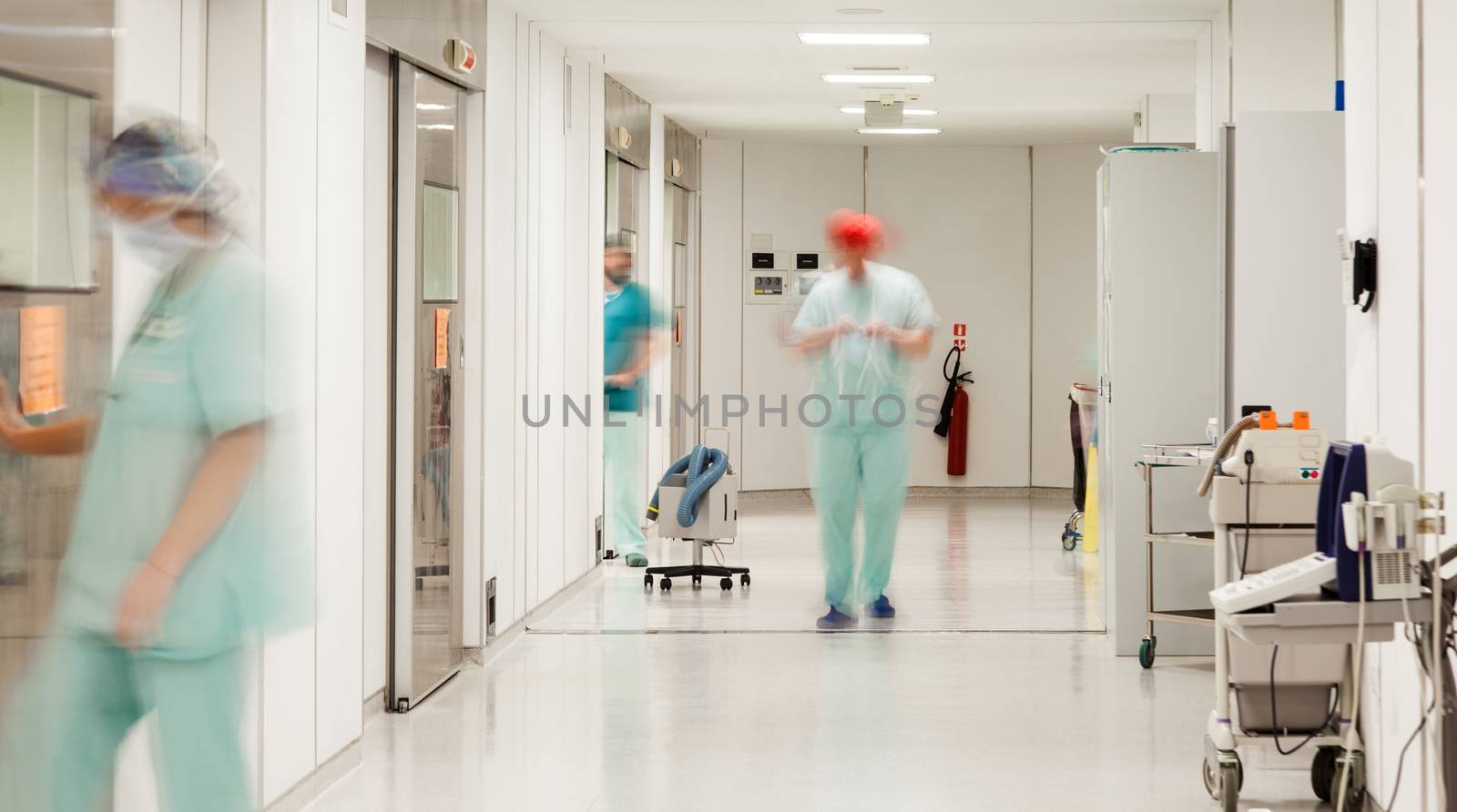 A sterile corridor to operating rooms in modern hospital with motion blurred figures of doctors and nurses.