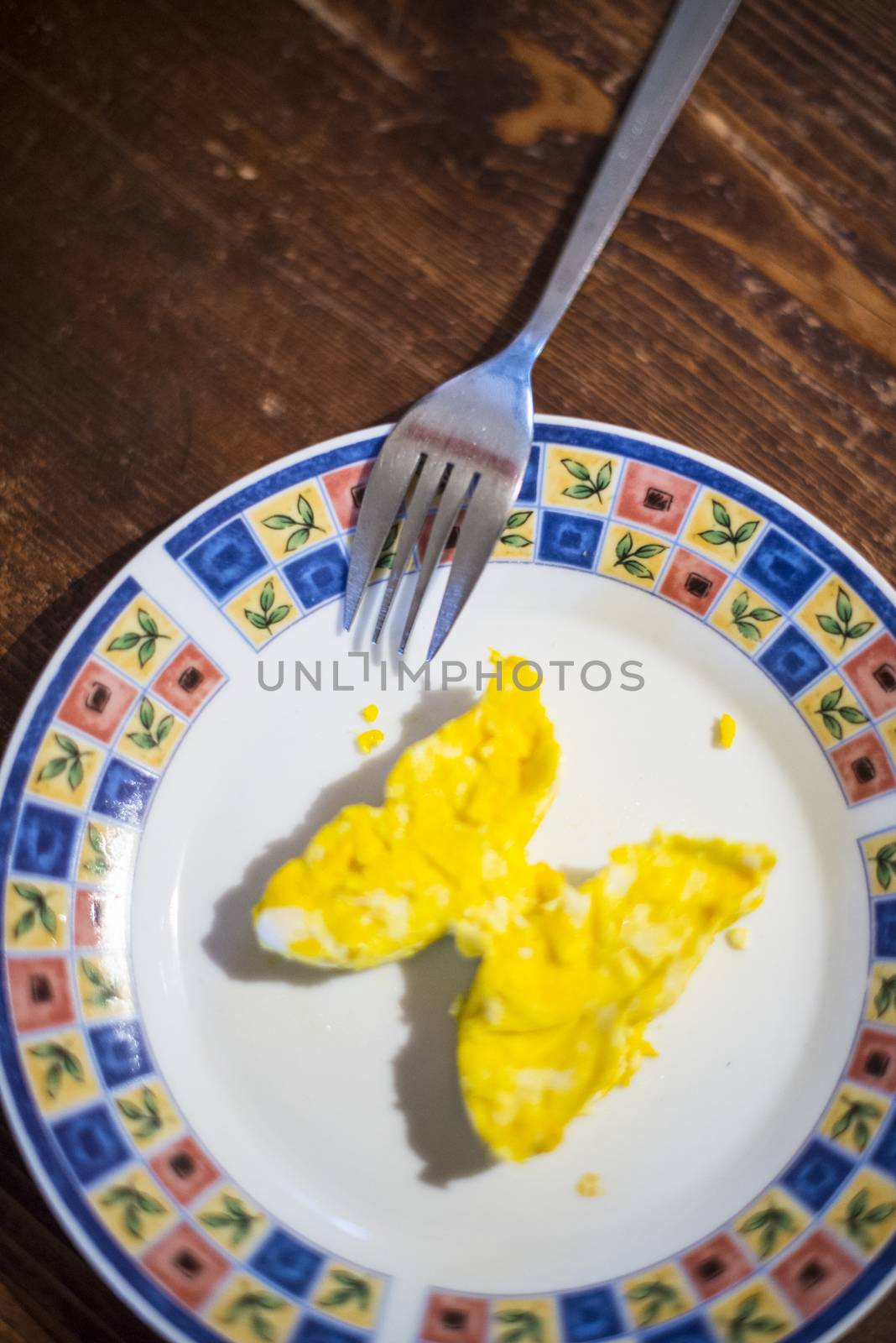dish with butterfly-shaped omelette and fork on dark wooden table