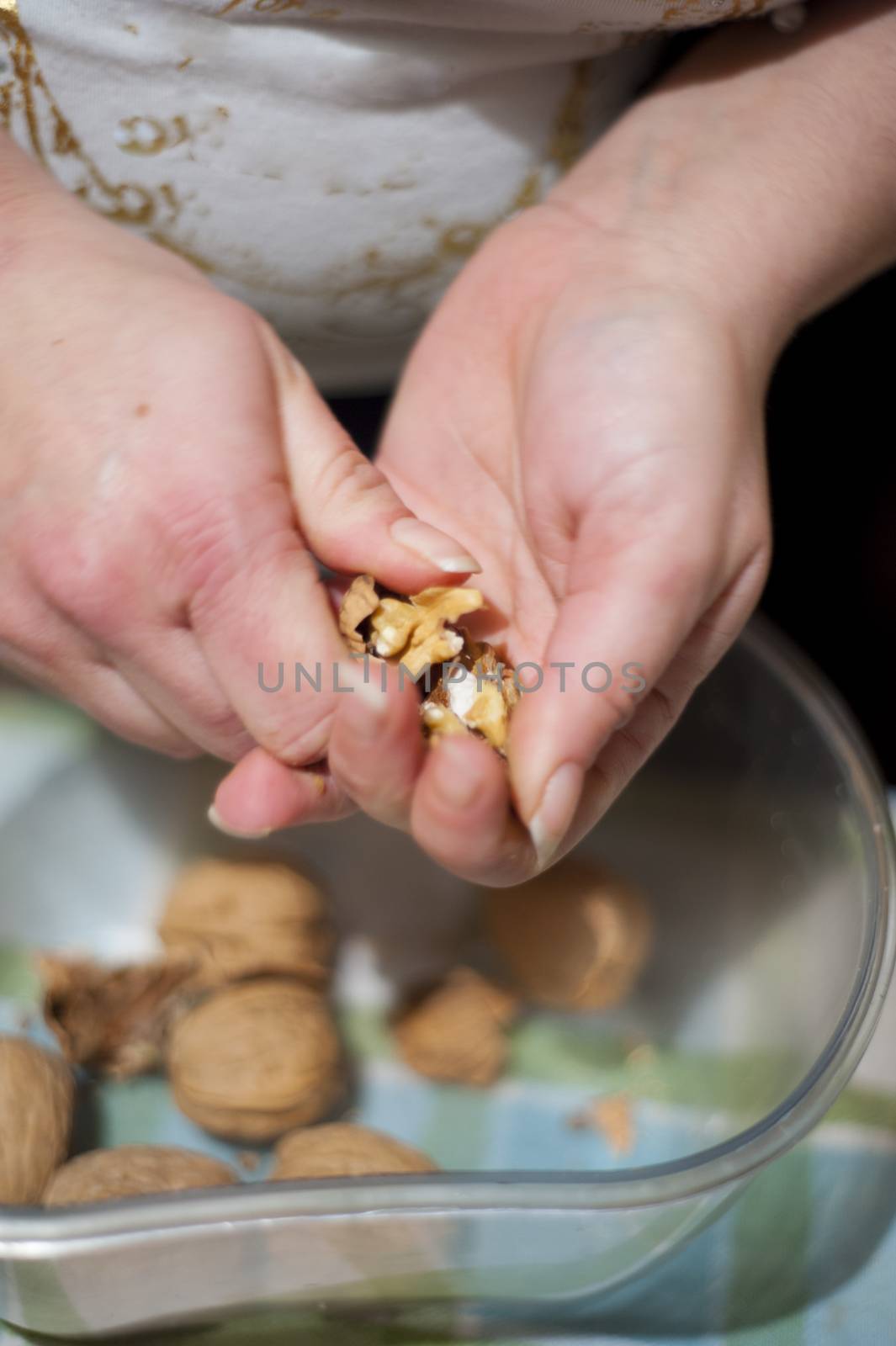 woman's hands open up pecan nuts in a bowl