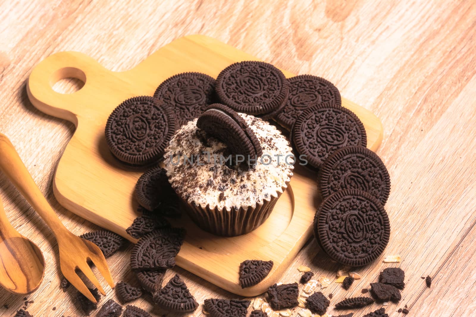 Chocolate cupcake and cookies are on wooden plate