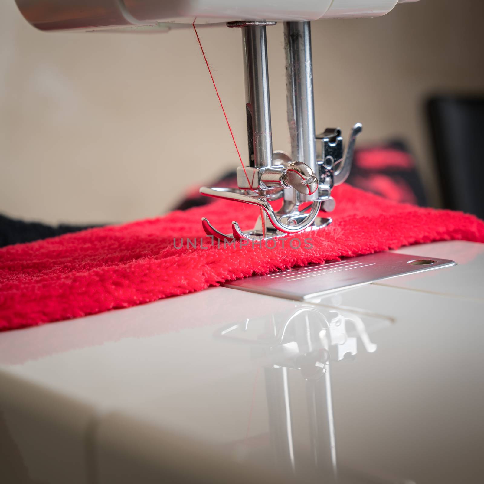 sewing machine close up and red cloth, sewing process in the phase of overstitching