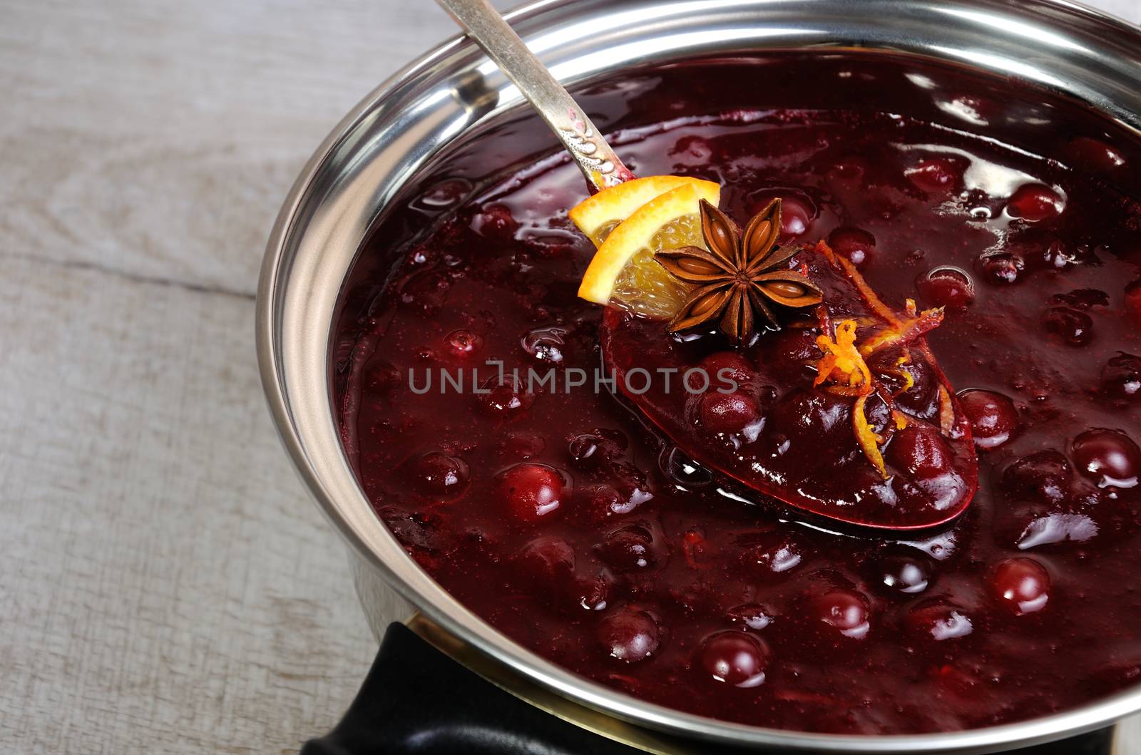 Freshly cooked cranberry sauce with orange peel and citrus slices in a saucepan