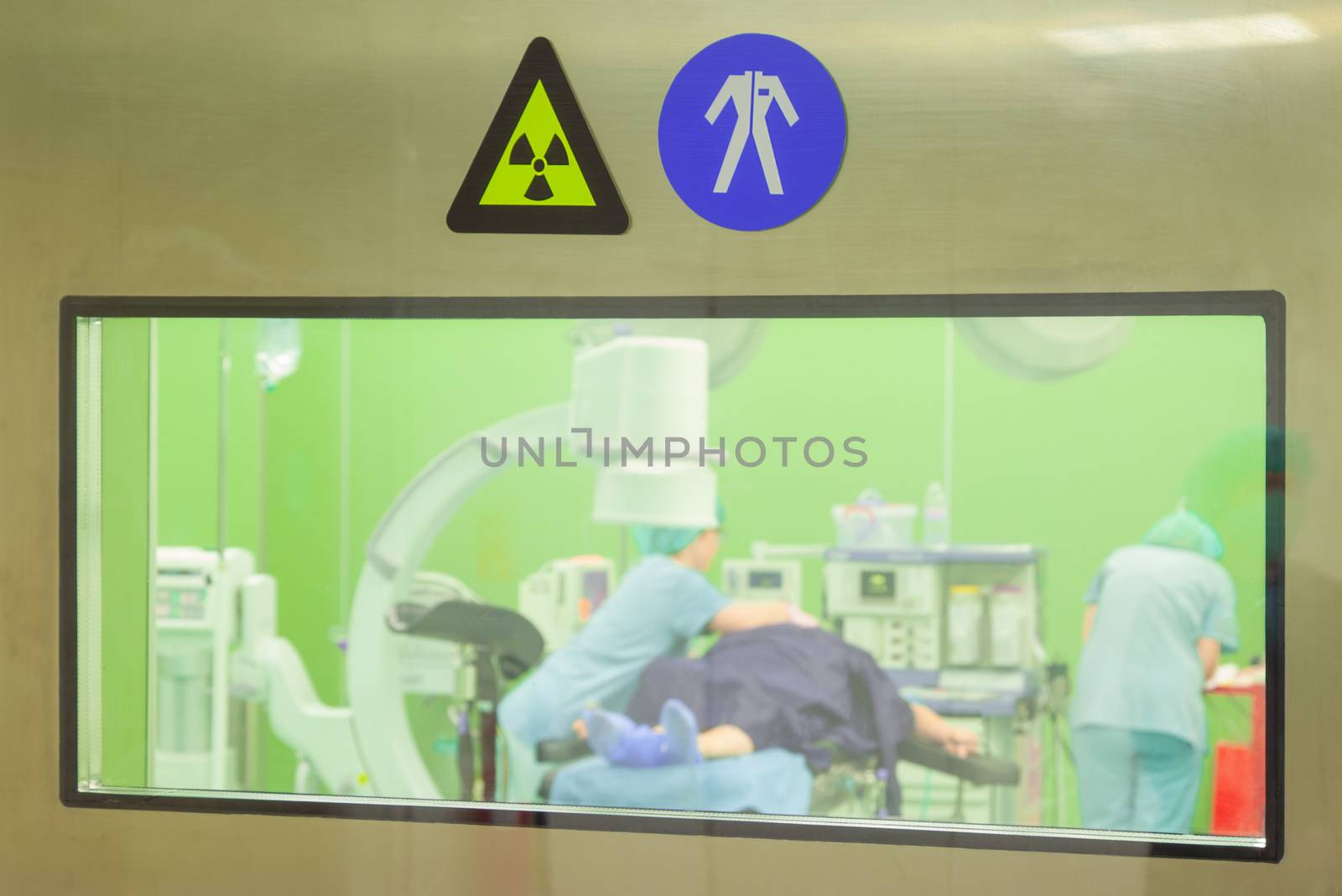 A sign for radiation and work clothes on a door of a surgery room while patient being prepared for operation.