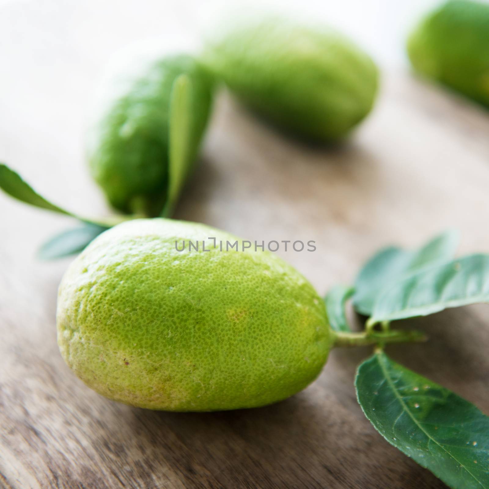 Pesticide free fresh organic lemons with leaves on wood background, imperfect insect bites.