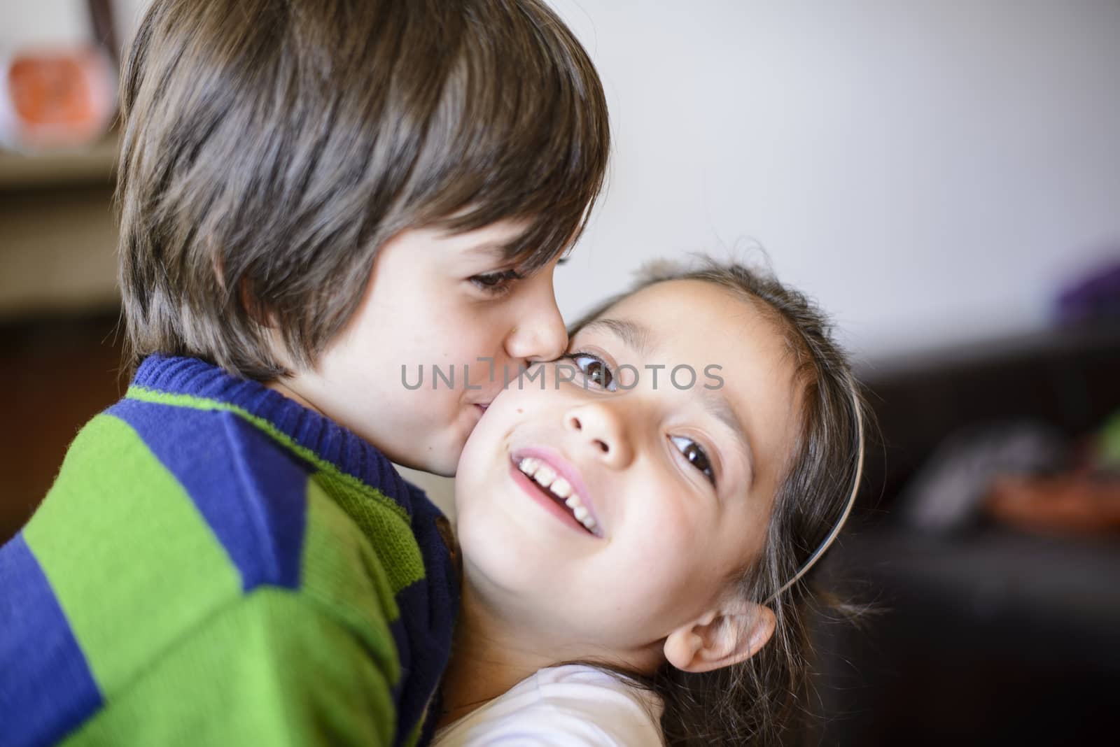 children brothers kiss on the cheek laughing and playing at home