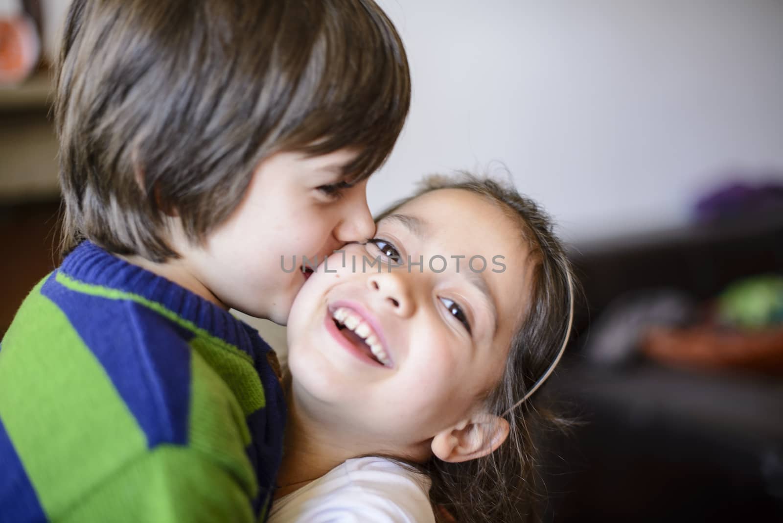 children brothers kiss on the cheek laughing and playing at home