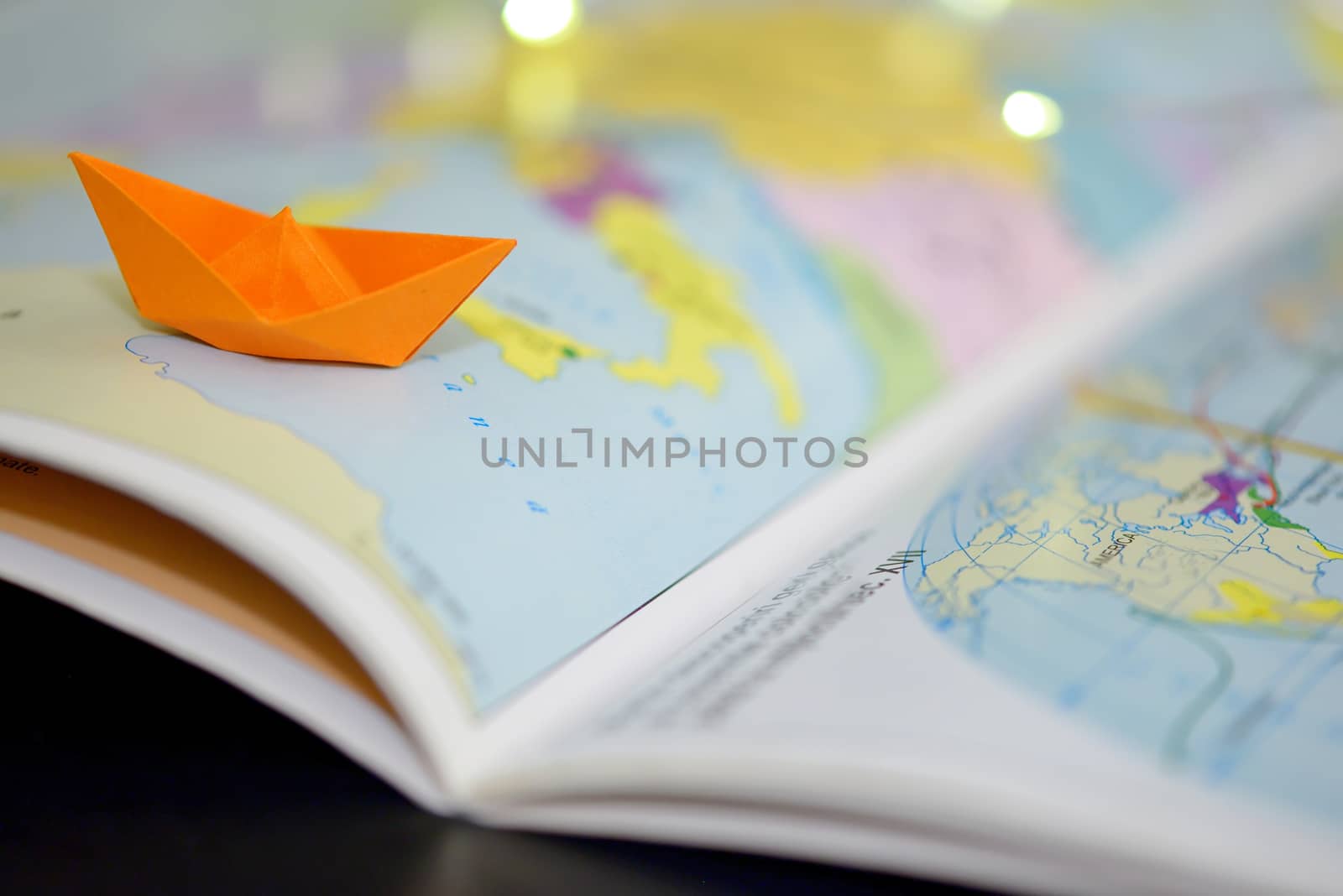 Paper boat on a atlas book map of the world