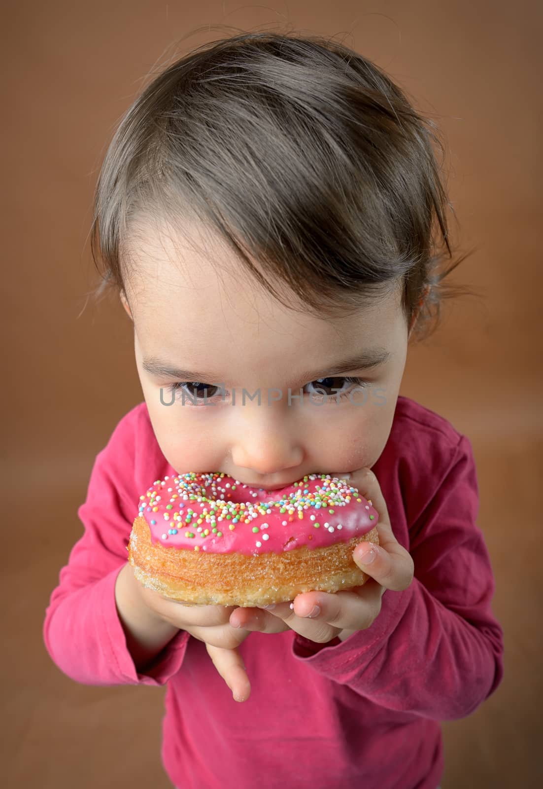 Little girl eating tasty donuts
