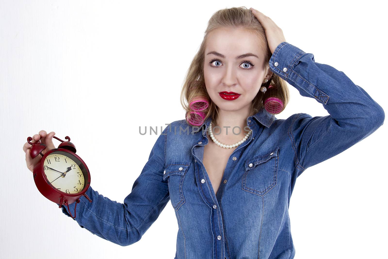 Frightened young woman in curlers with alarm clock