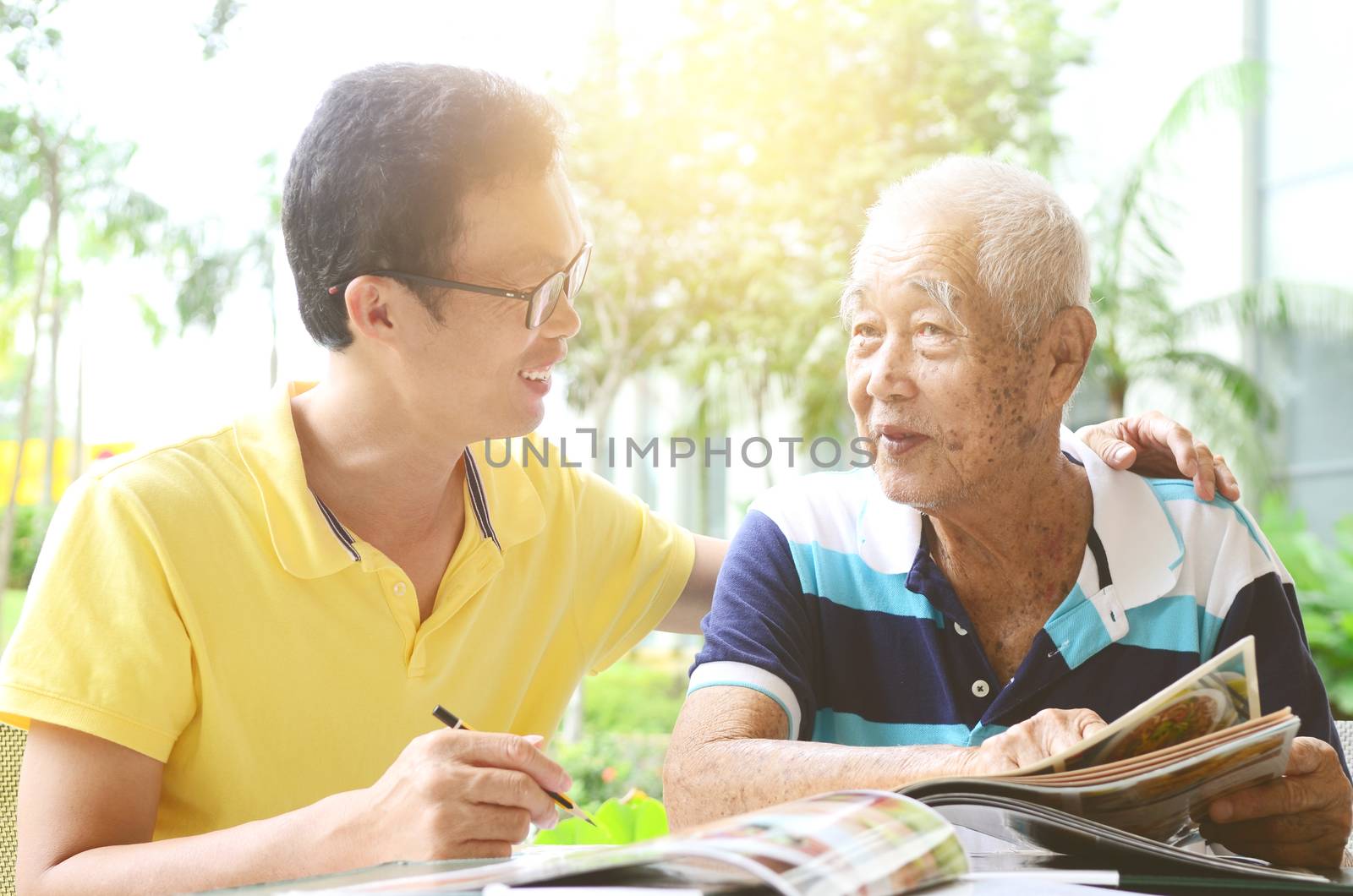 Asian senior man and son in the restaurant,ordering food by looking at the menu.