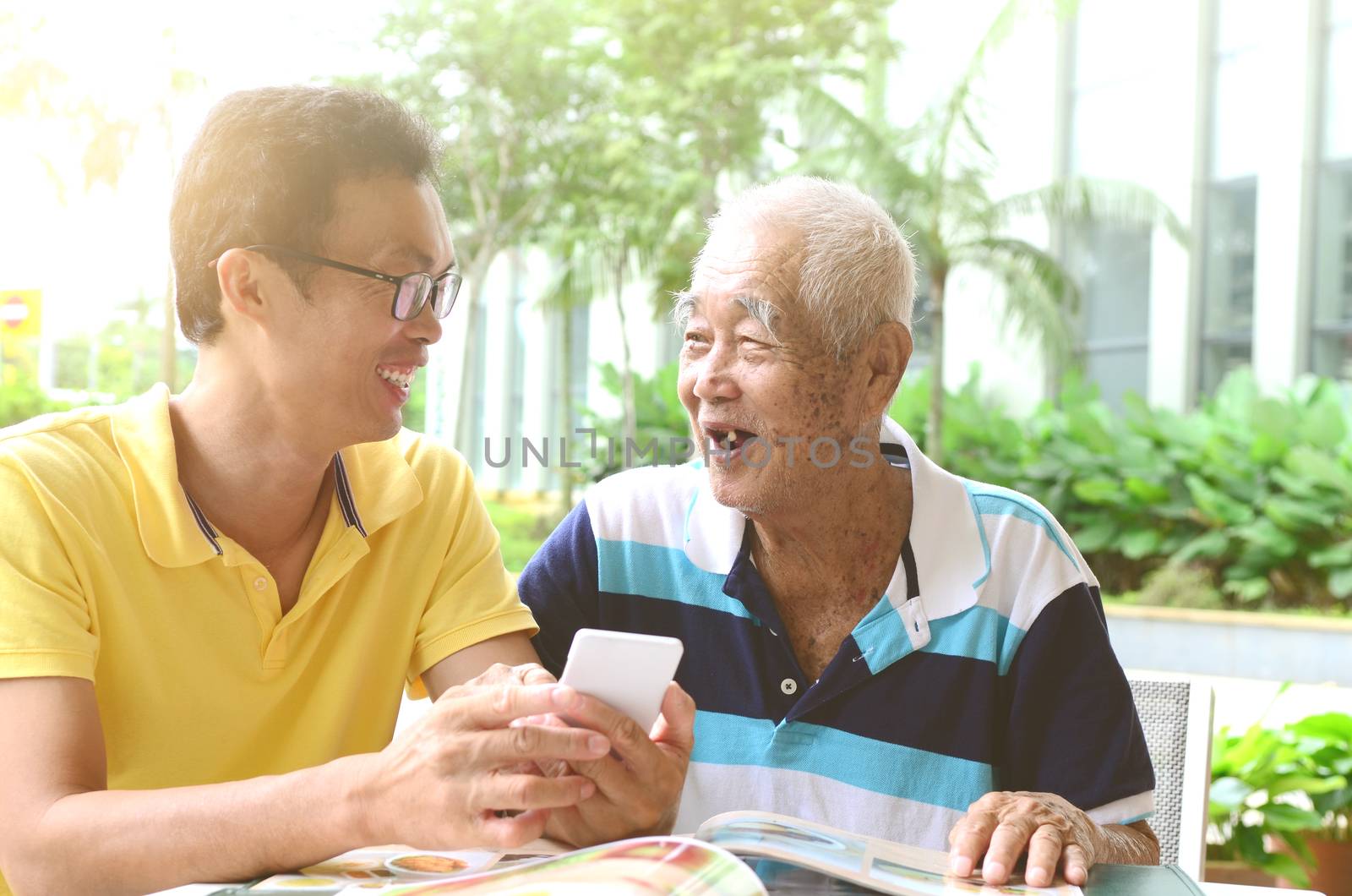 Asian senior man and son using mobile (smart phone) ,ordering food  in the restaurant .Technology concept.