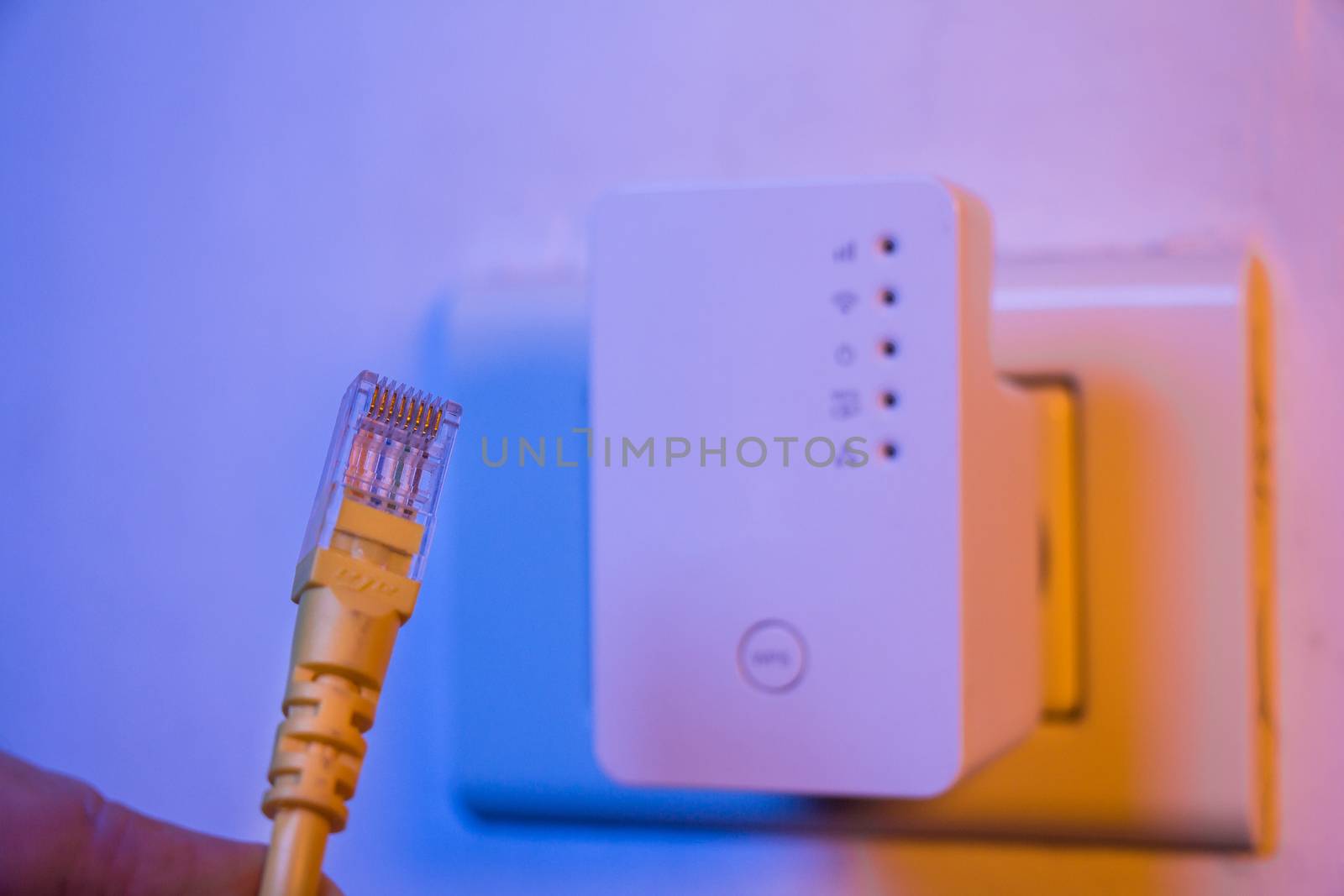 Closeup of ethernet cable. WiFi extender device in electrical socket on the wall on the background. The device is in access point mode that help to extend wireless network in home or office.
