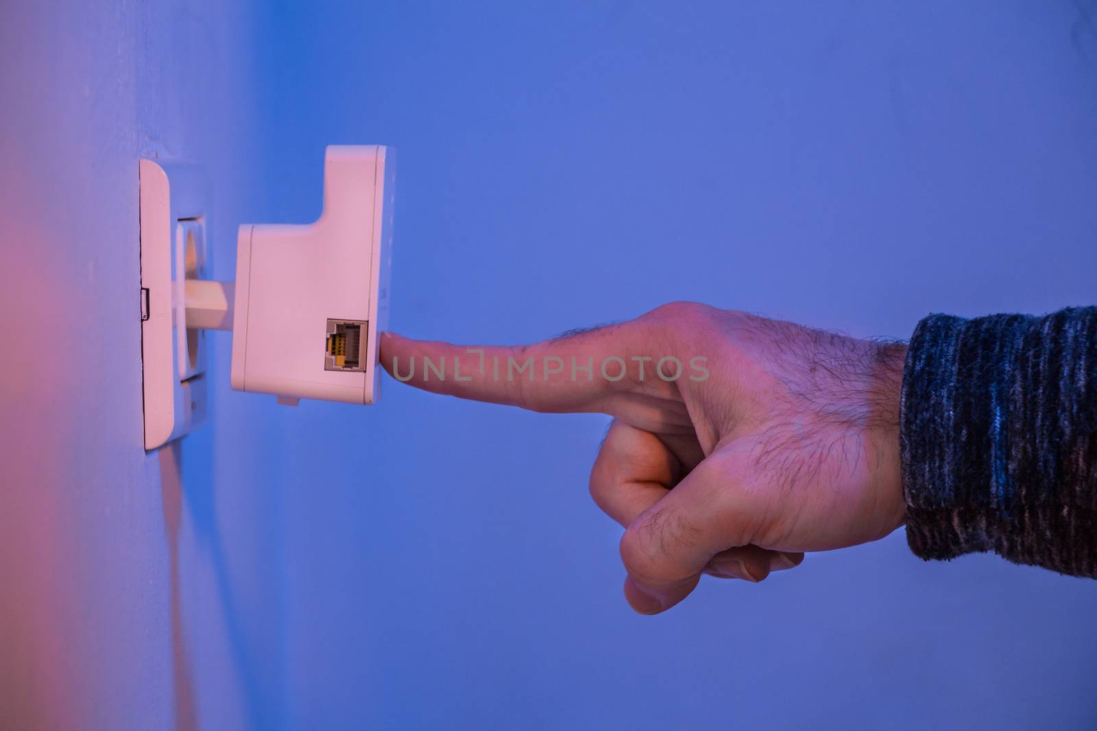 Man press with his finger on WPS button on WiFi repeater which i by wavemovies