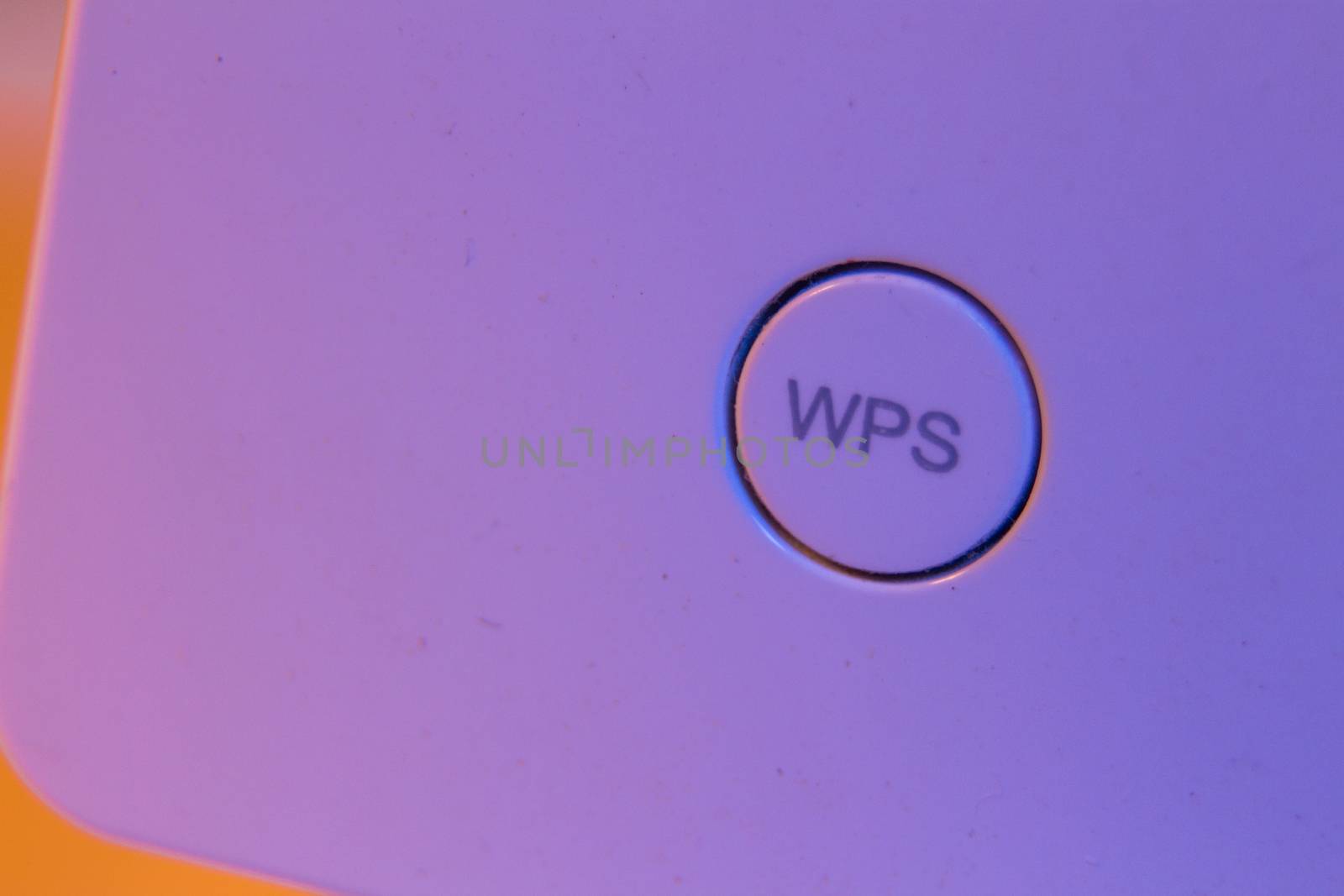 Macro closeup on WiFi repeater WPS button. The device is in electrical socket on the wall. It help to extend wireless network in home or office.