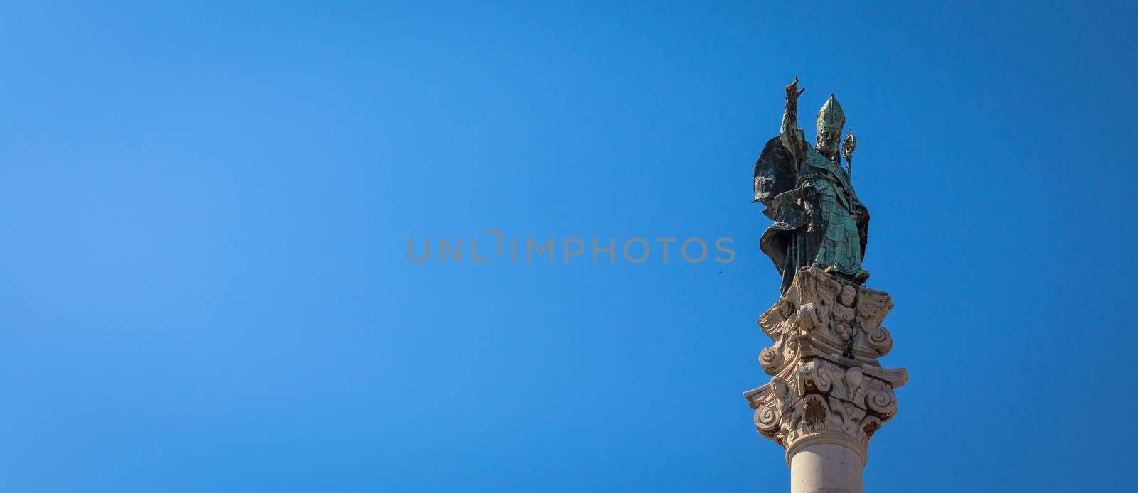 The symbol of Lecce town (Italy): Saint Oronzo (Sant'Oronzo) posed on the column at the center of the main town Square. Blue backgroud with copy space.