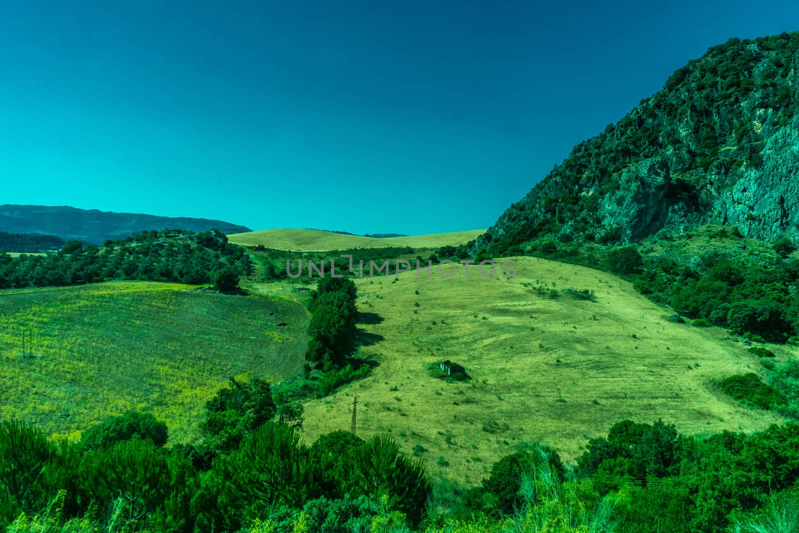 Greenery, Mountains, Farms and Fields on the outskirts of Ronda Spain, Europe on a hot summer day with clear blue skies