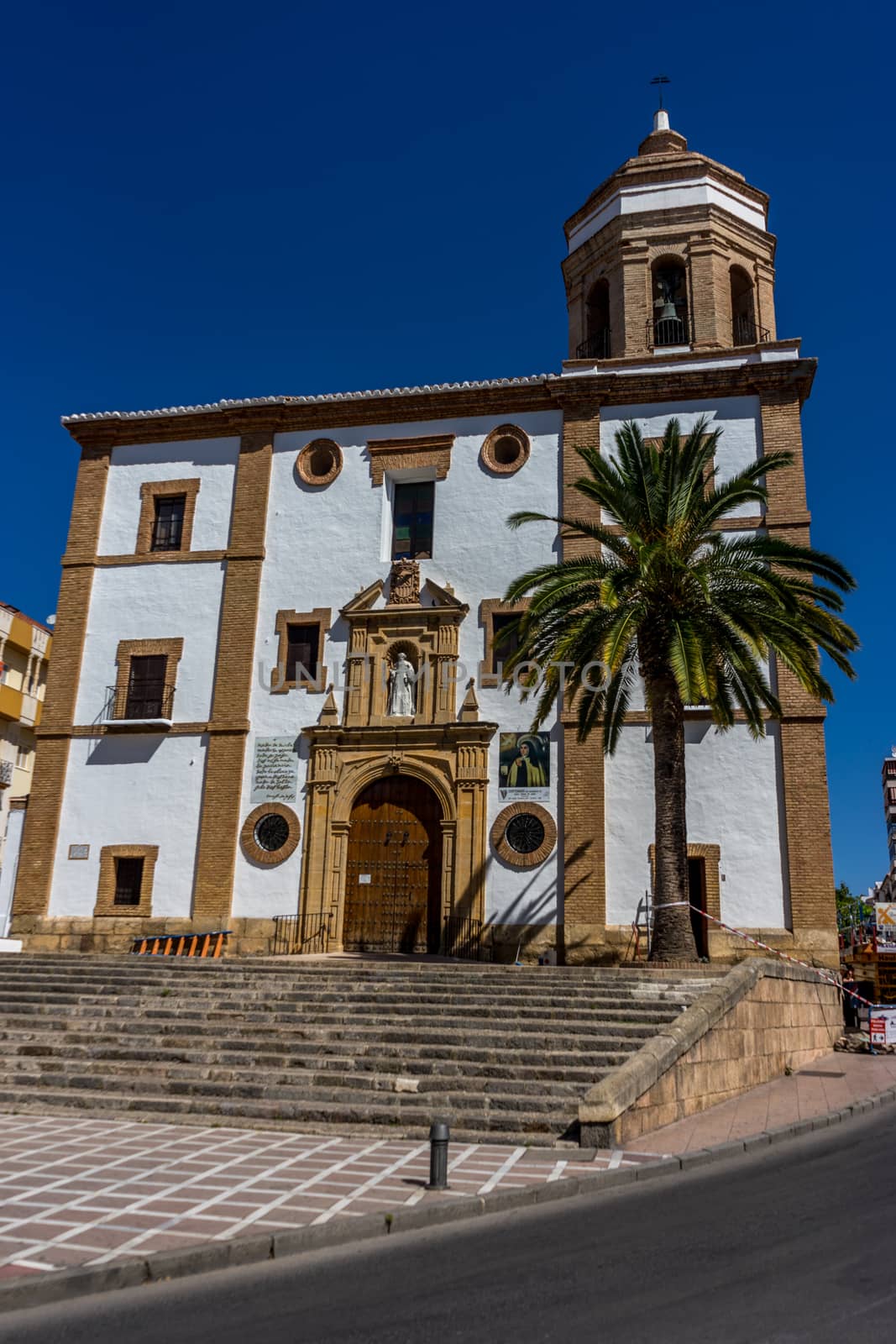 A church in the city of of Ronda Spain, Europe on a hot summer day with clear blue skies with a palm tree in the front