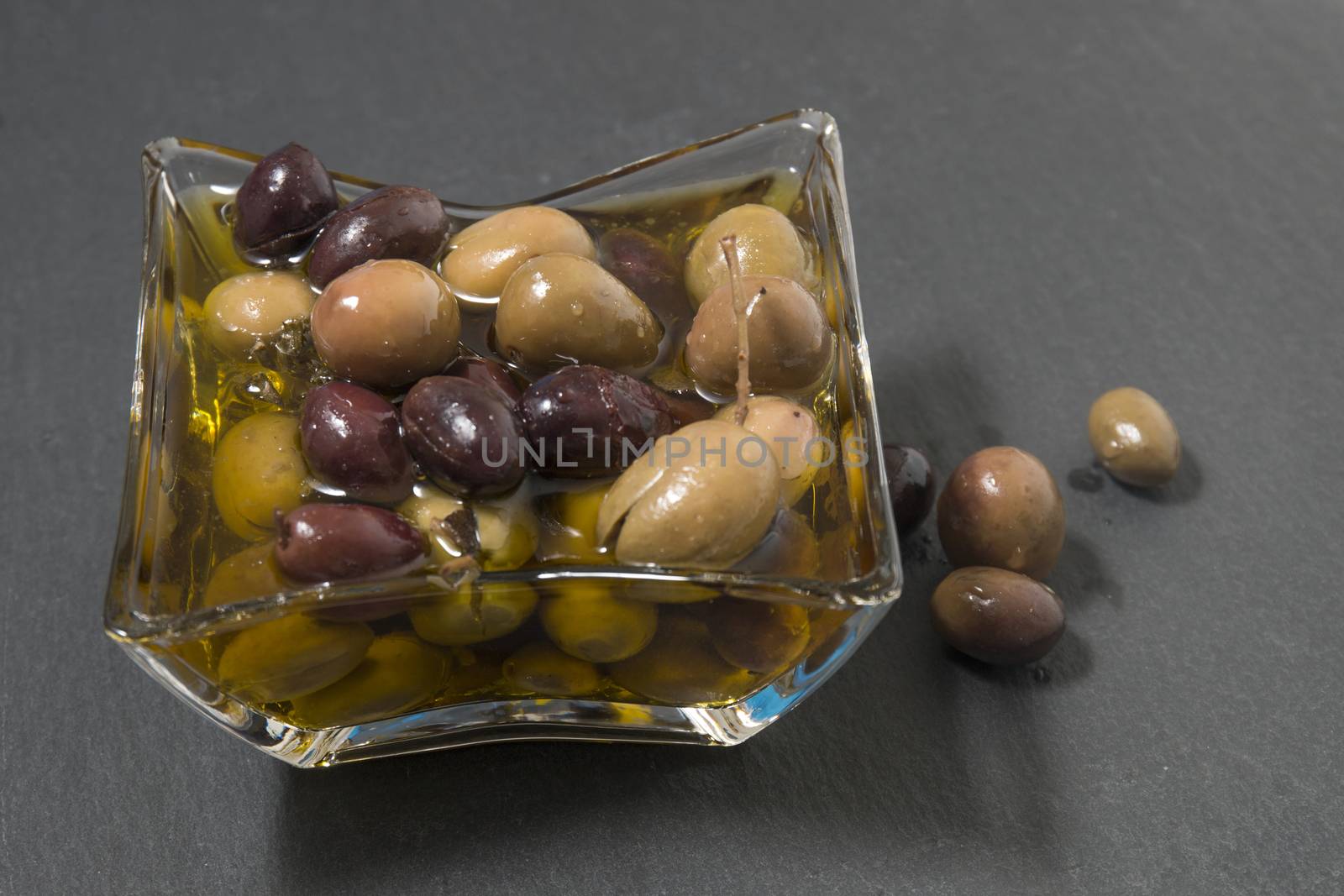 Olives with olive oil on a shale stone.