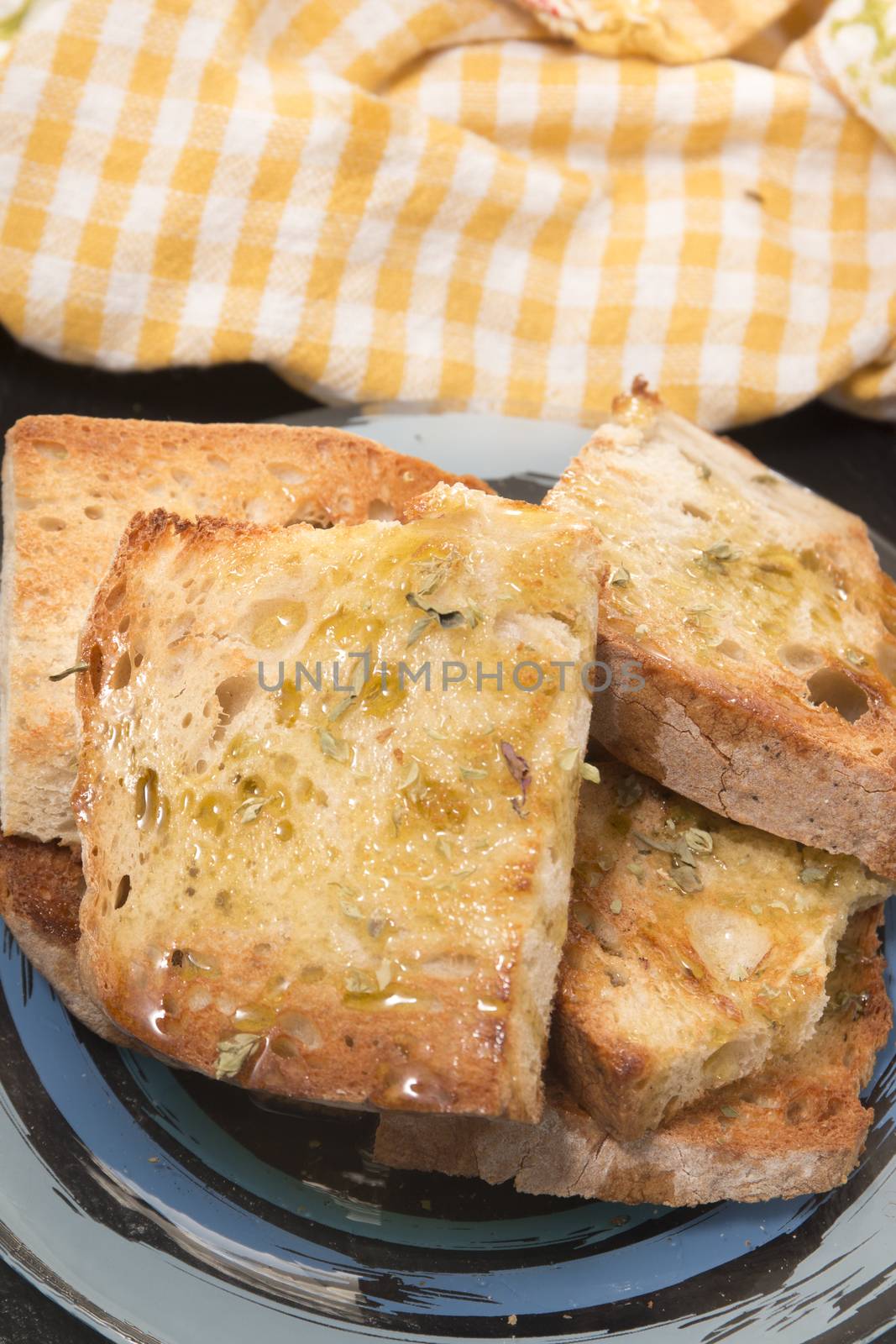 Traditional Portuguese bread toasted with virgin olive oil and oregano herbs on a shale stone.