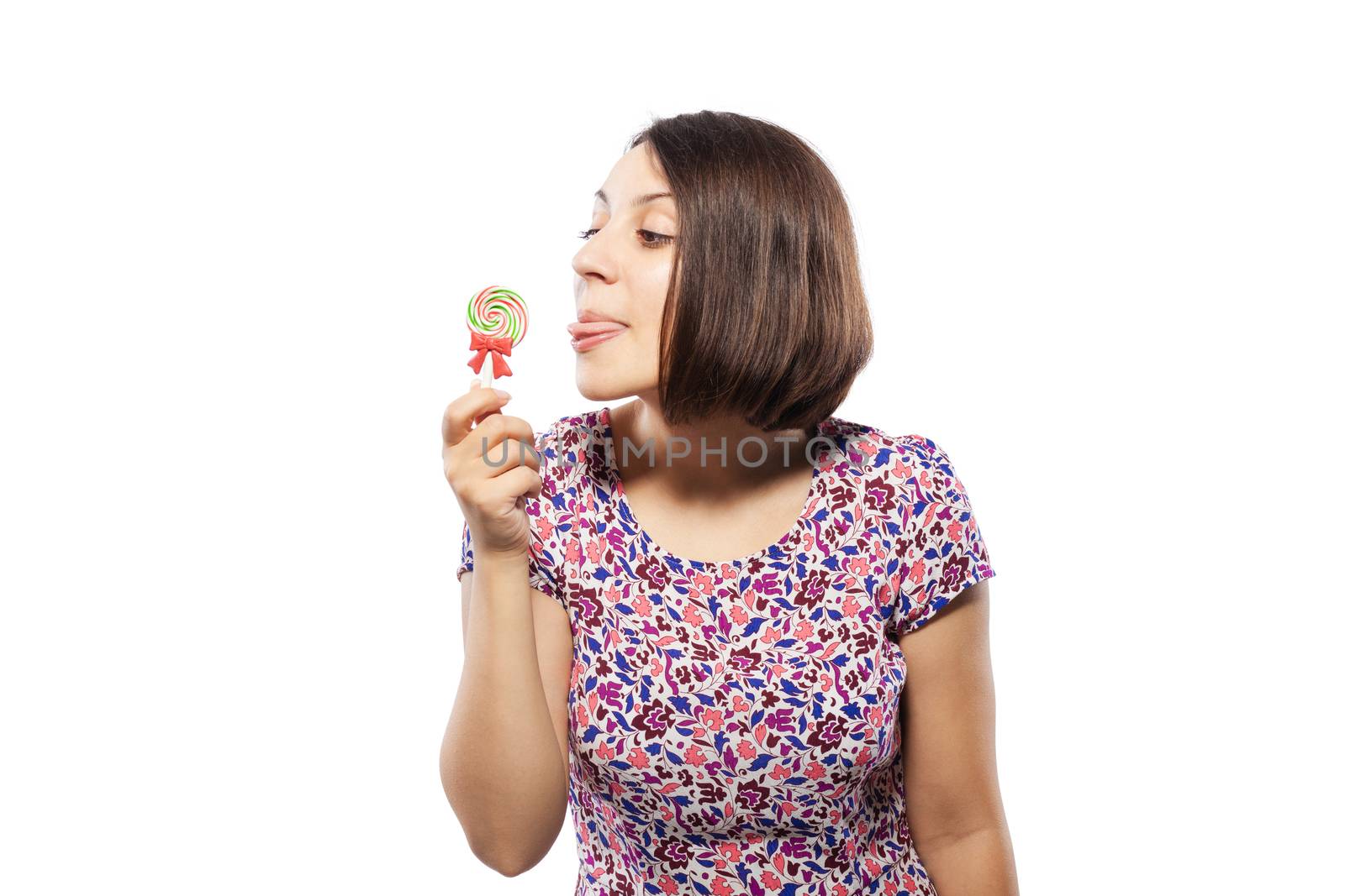 happy girl in pink dress trying to lick a spiral lollipop