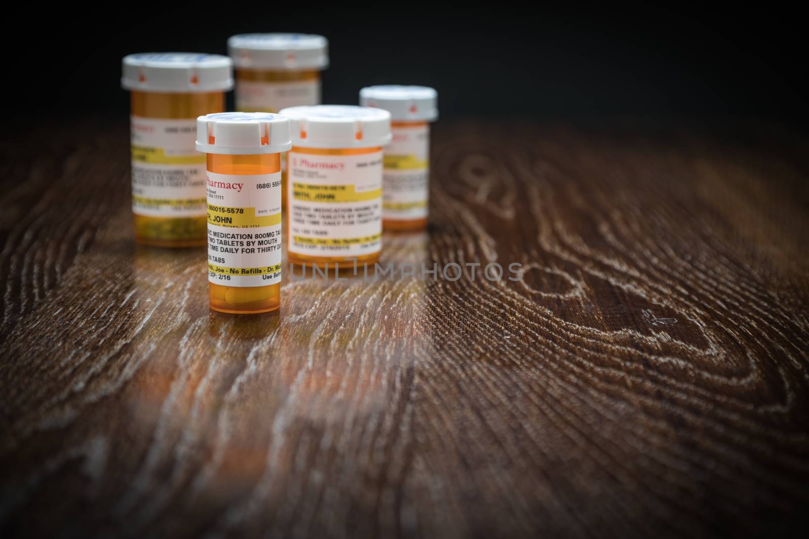 Variety of Non-Proprietary Prescription Medicine Bottles on Reflective Wooden Surface.