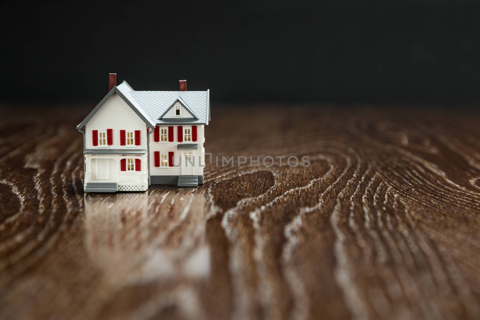 Model Home on Reflective Wooden Surface. by Feverpitched