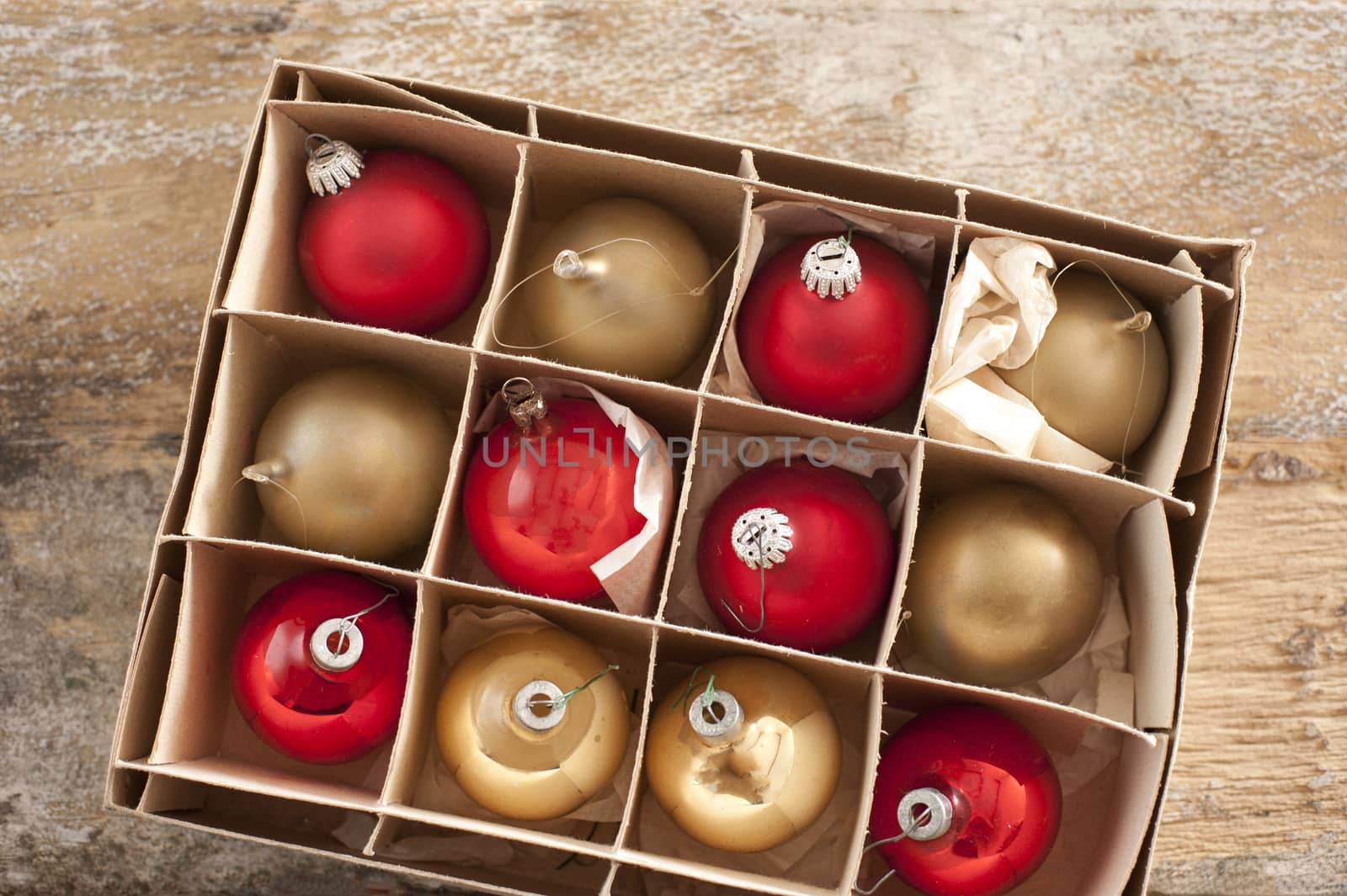 Top down view on golden colored and red christmas tree ornament balls inside cardboard box