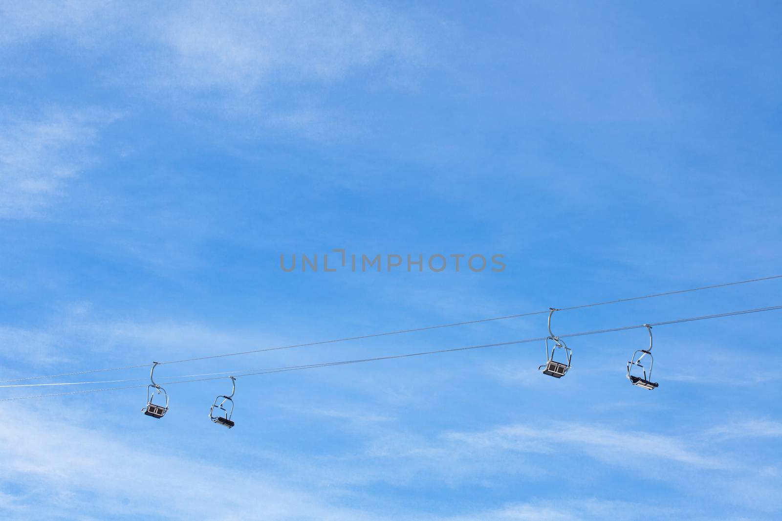 ski chair lift with two cables and four double seats, against blue sky