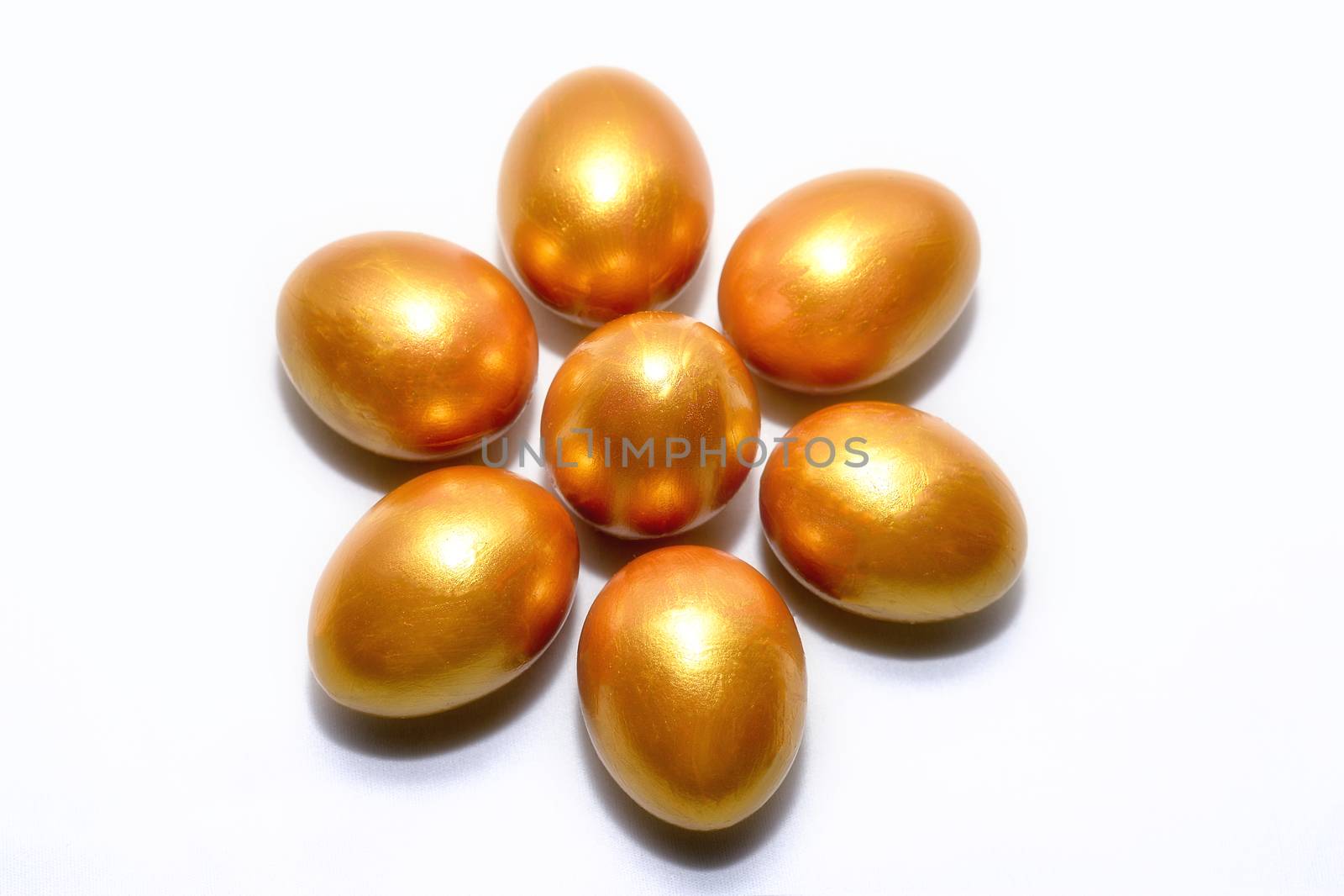 Golden eggs lie in the form of a flower on a white background, the concept of financial success.