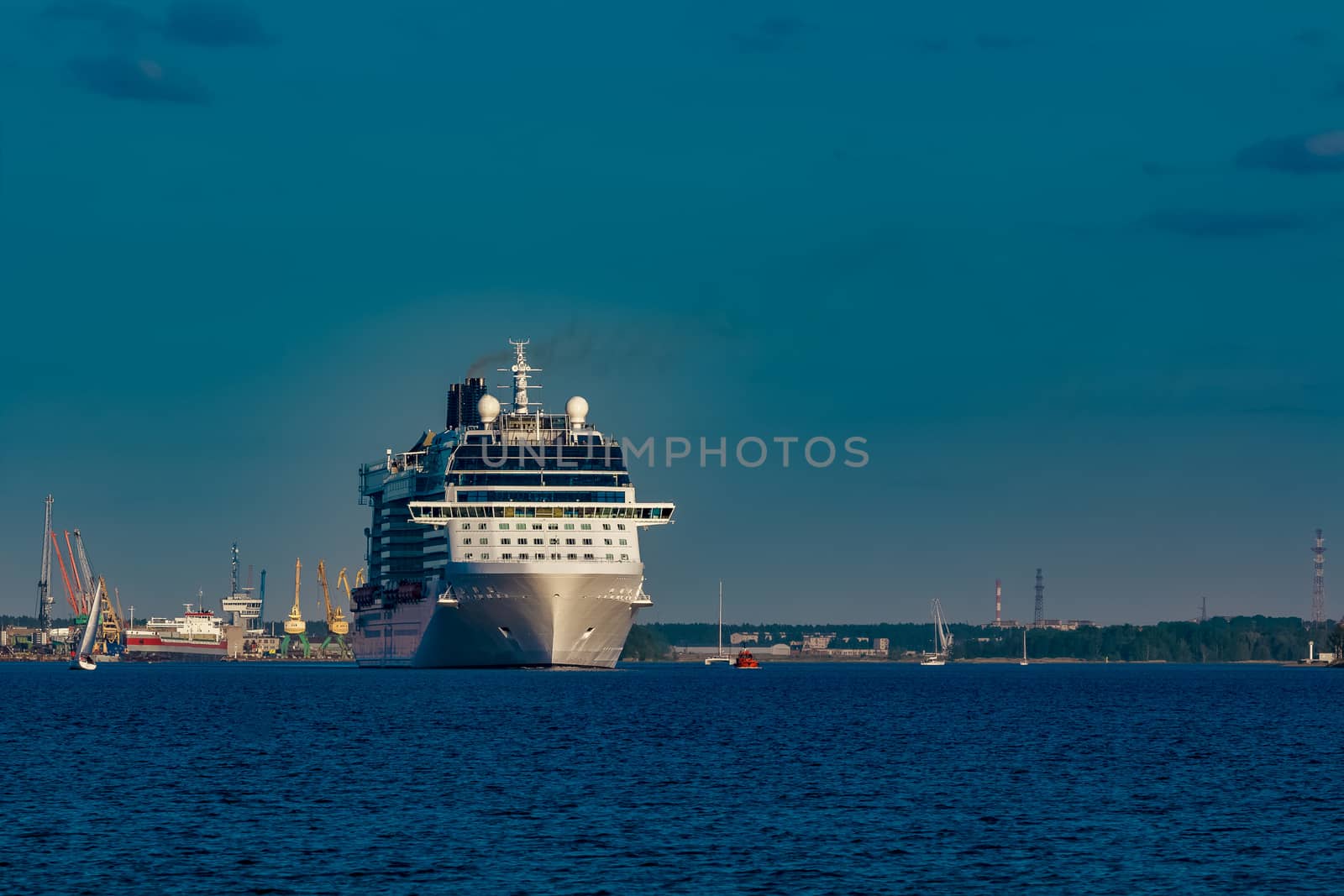 Giant white passenger ship moving past the port on a clear day