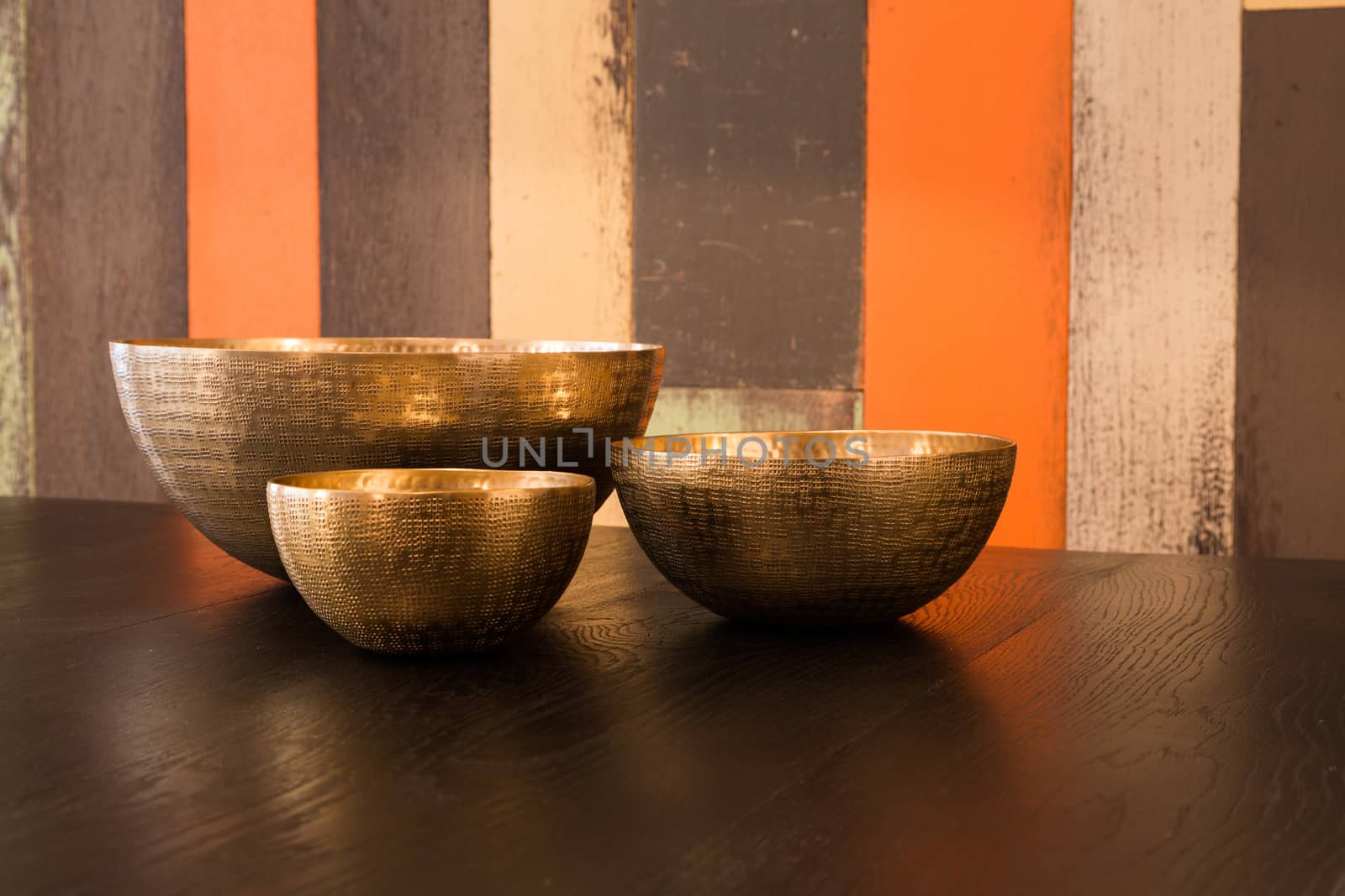 Three empty decorated metal bowls on a table