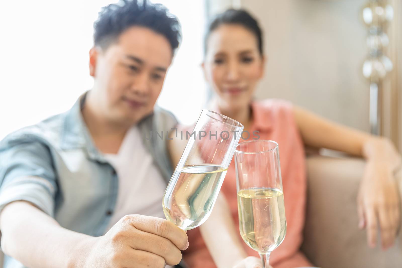 Young Couples celebrate together with wine  in bedroom of contemporary house for modern lifestyle concept (Focus at glasses)