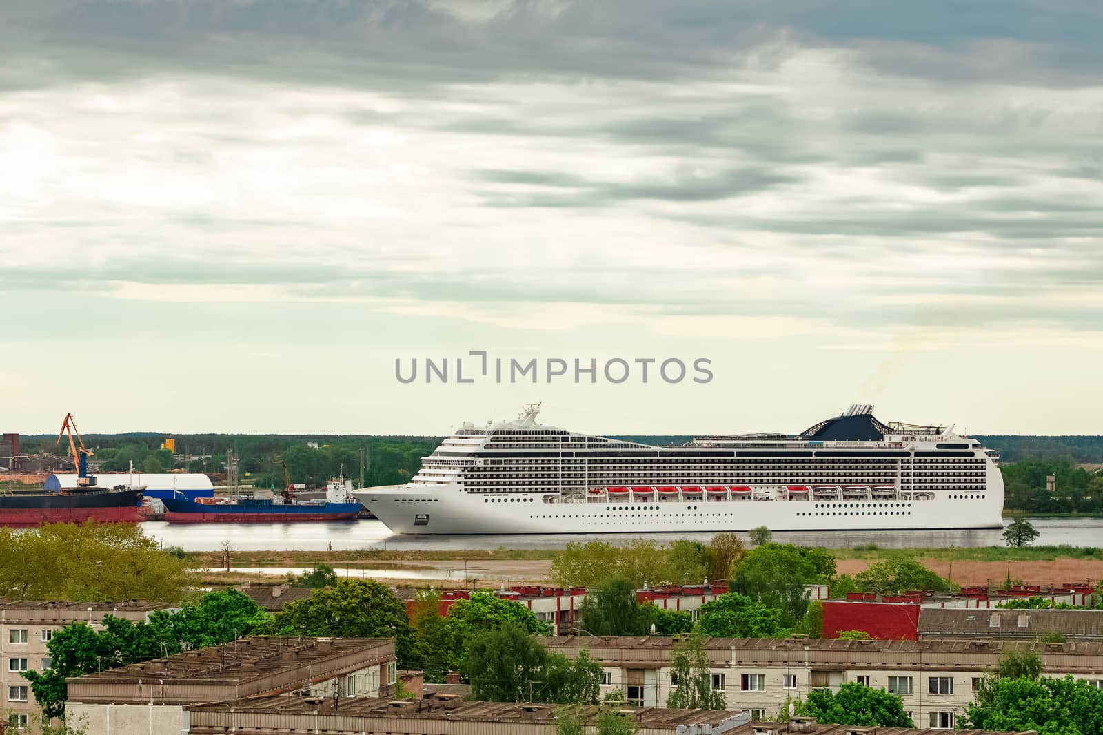 Big white cruise liner sailing past the cargo port