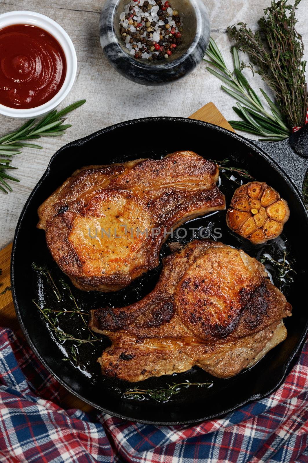 Roasted pork loin steak in a frying pan with tomato sauce and spices