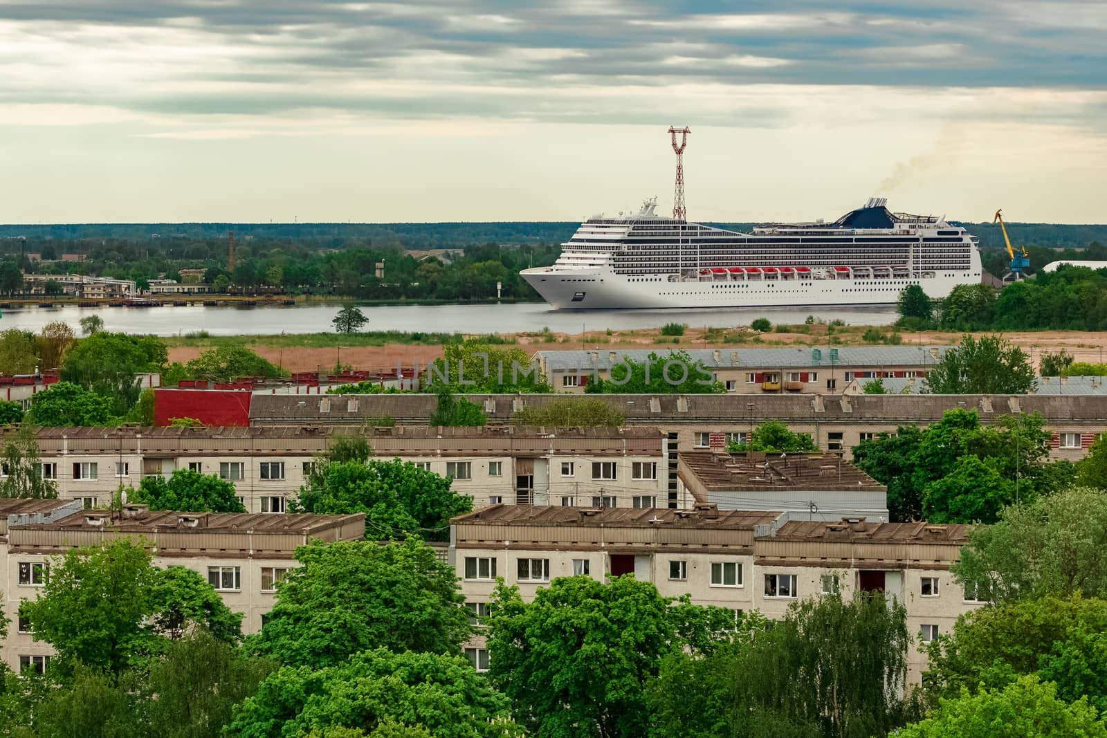 Big white cruise liner sailing past the cargo port