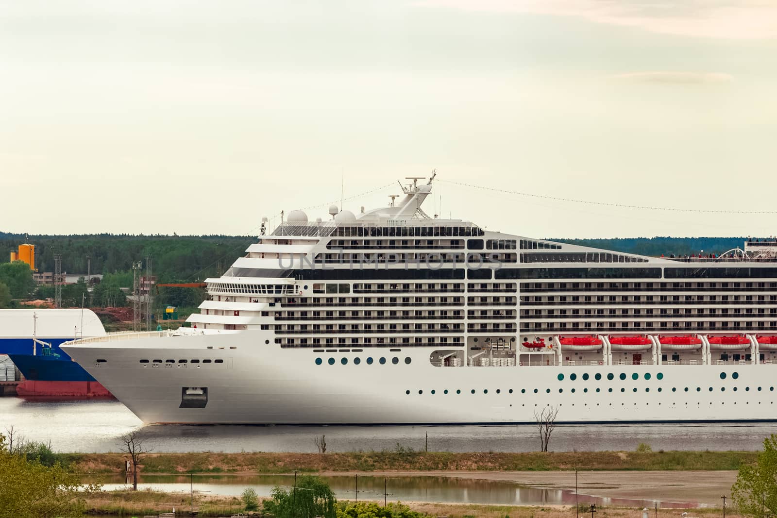 Big white cruise liner sailing past the cargo port