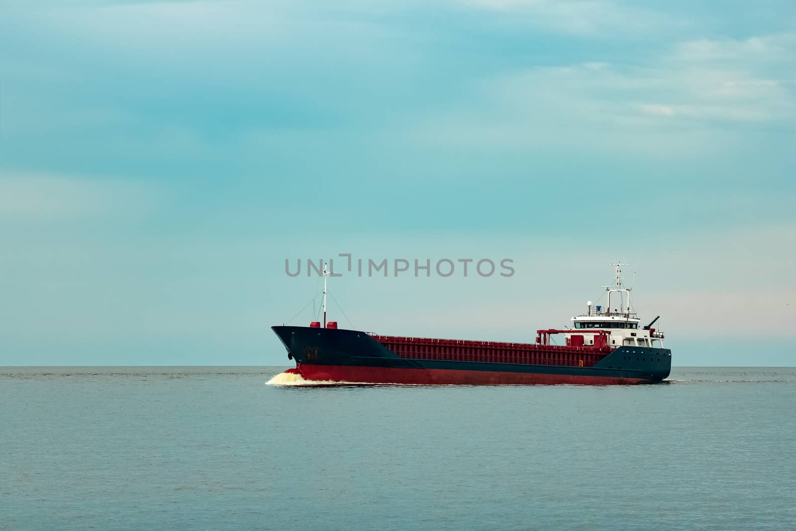 Merchandise import. Large blue cargo ship moving to Riga port