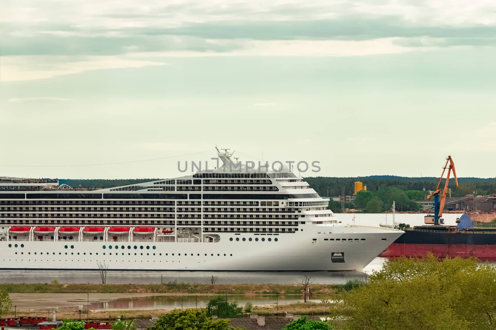 Big white cruise liner sailing past the cargo port