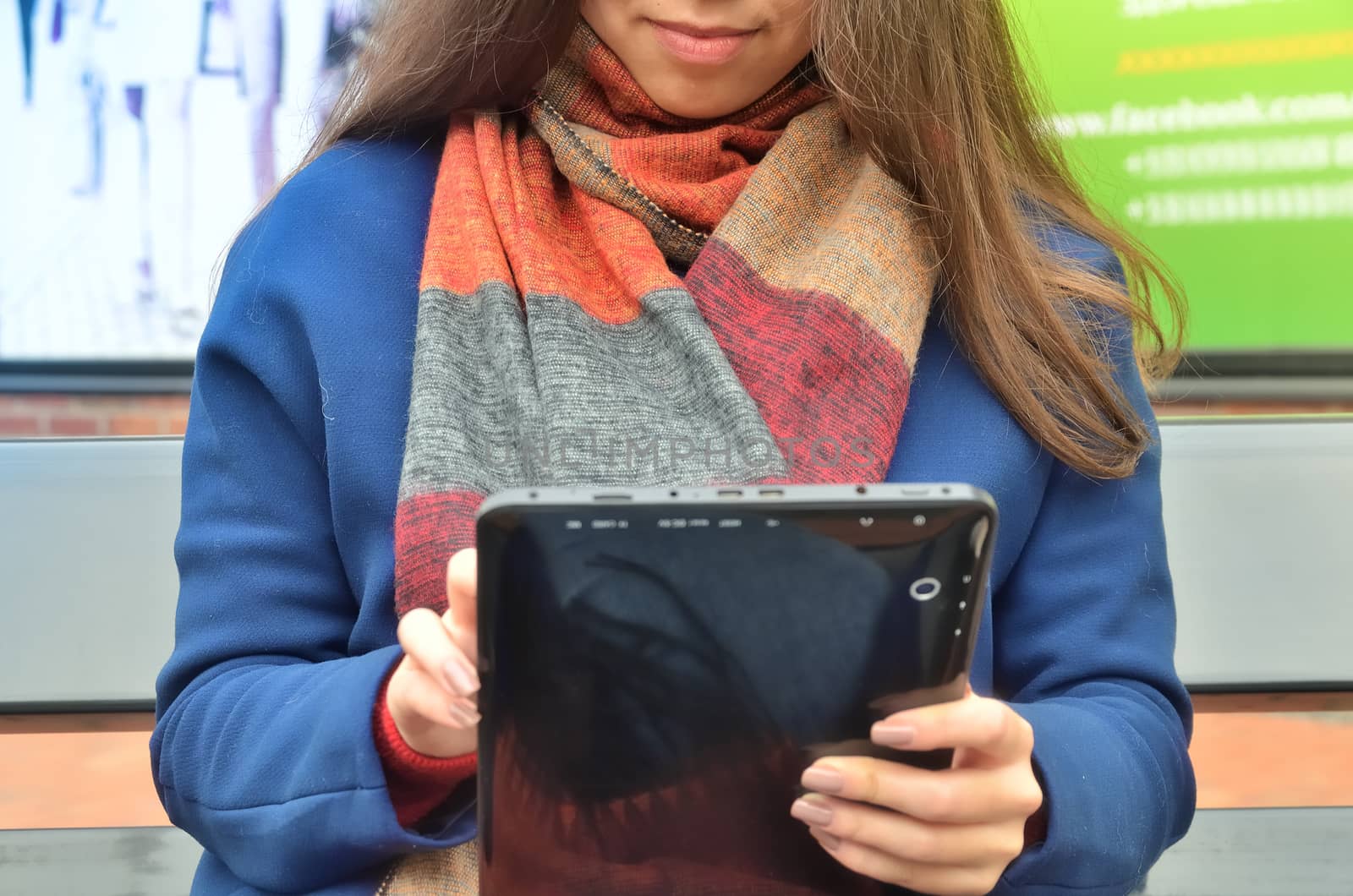 A woman is sitting on a bench and holding a black tablet by xzgorik