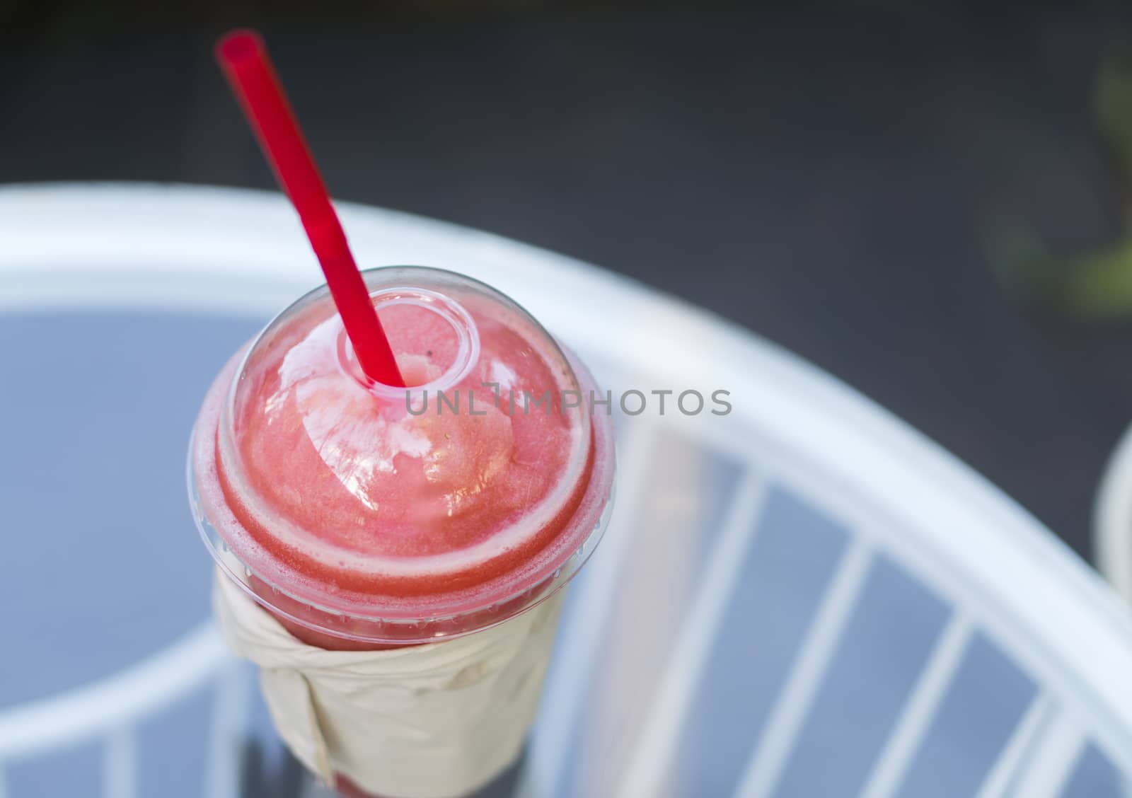 Closeup of watermelon smoothie in plastic glass on table, selective focus