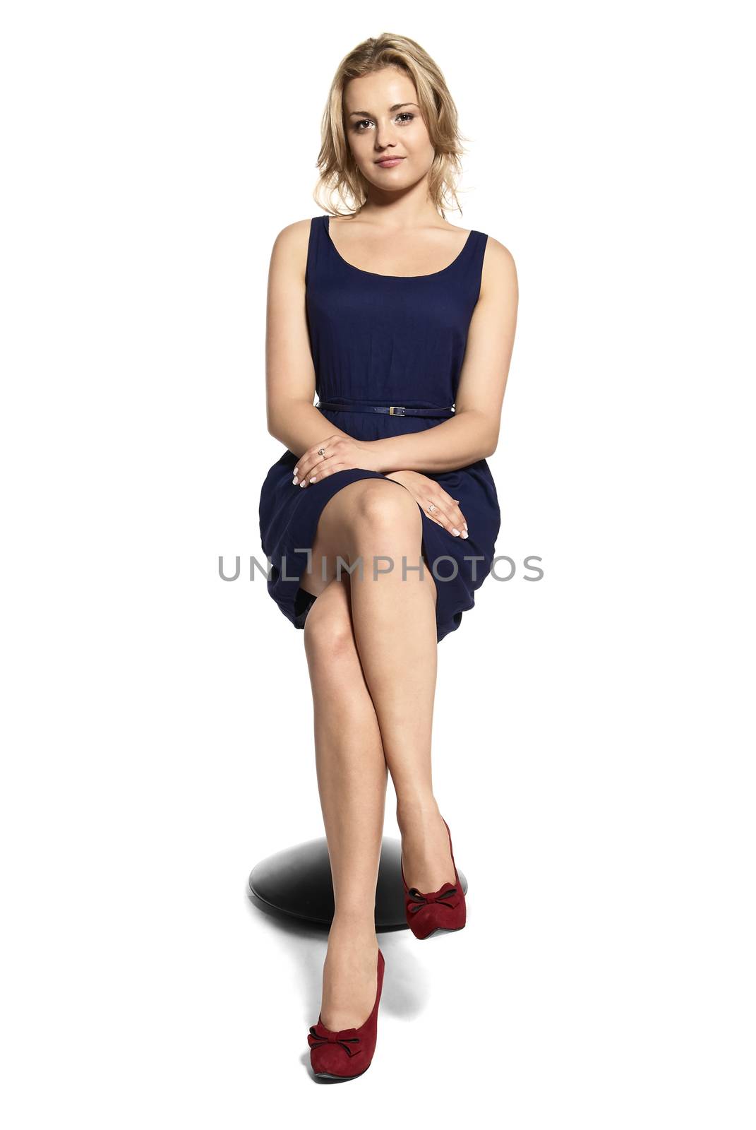 Studio shot of attractive young woman sitting on a stool and waiting for... Isolated on white background.