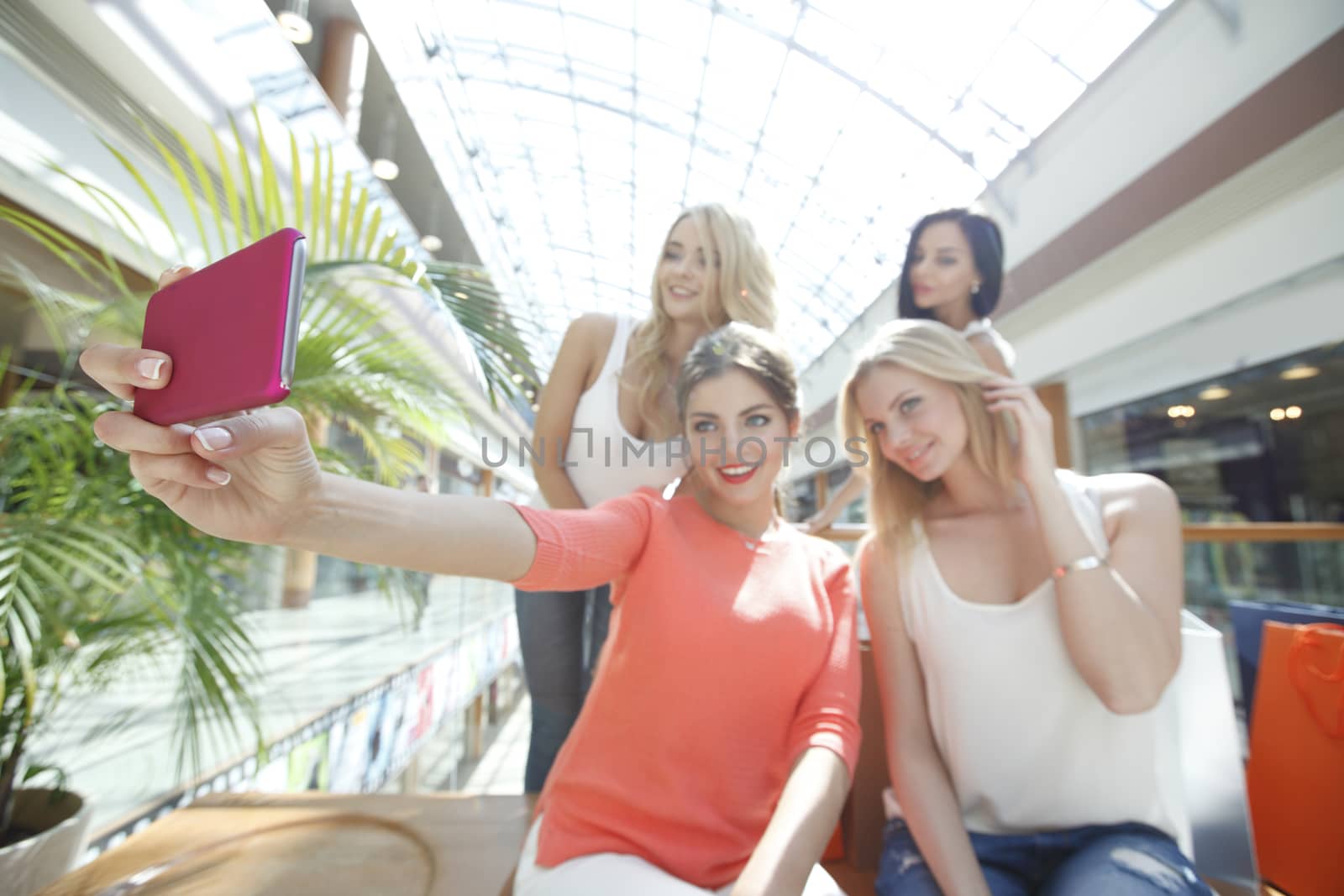 Happy female friends taking selfie in shopping mall