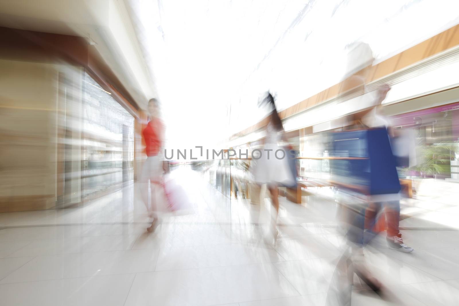 Women walking fast in shopping mall with bags