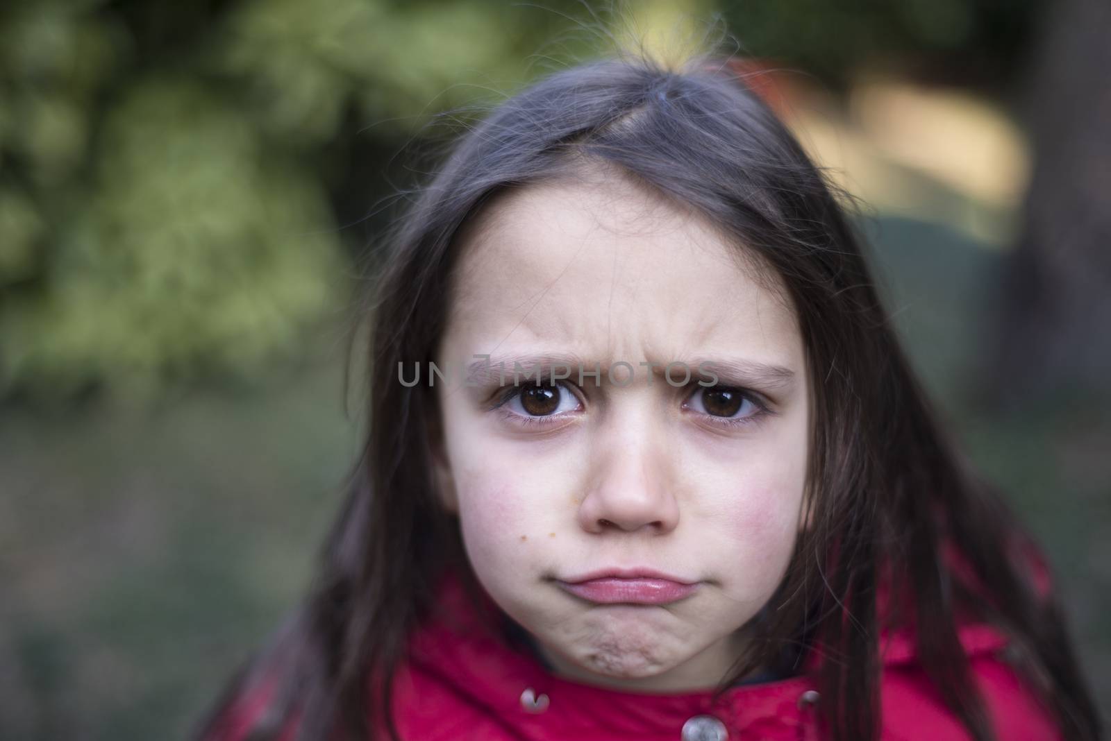 portrait of 7 year old girl in outdoor in the garden in winter with red jacket