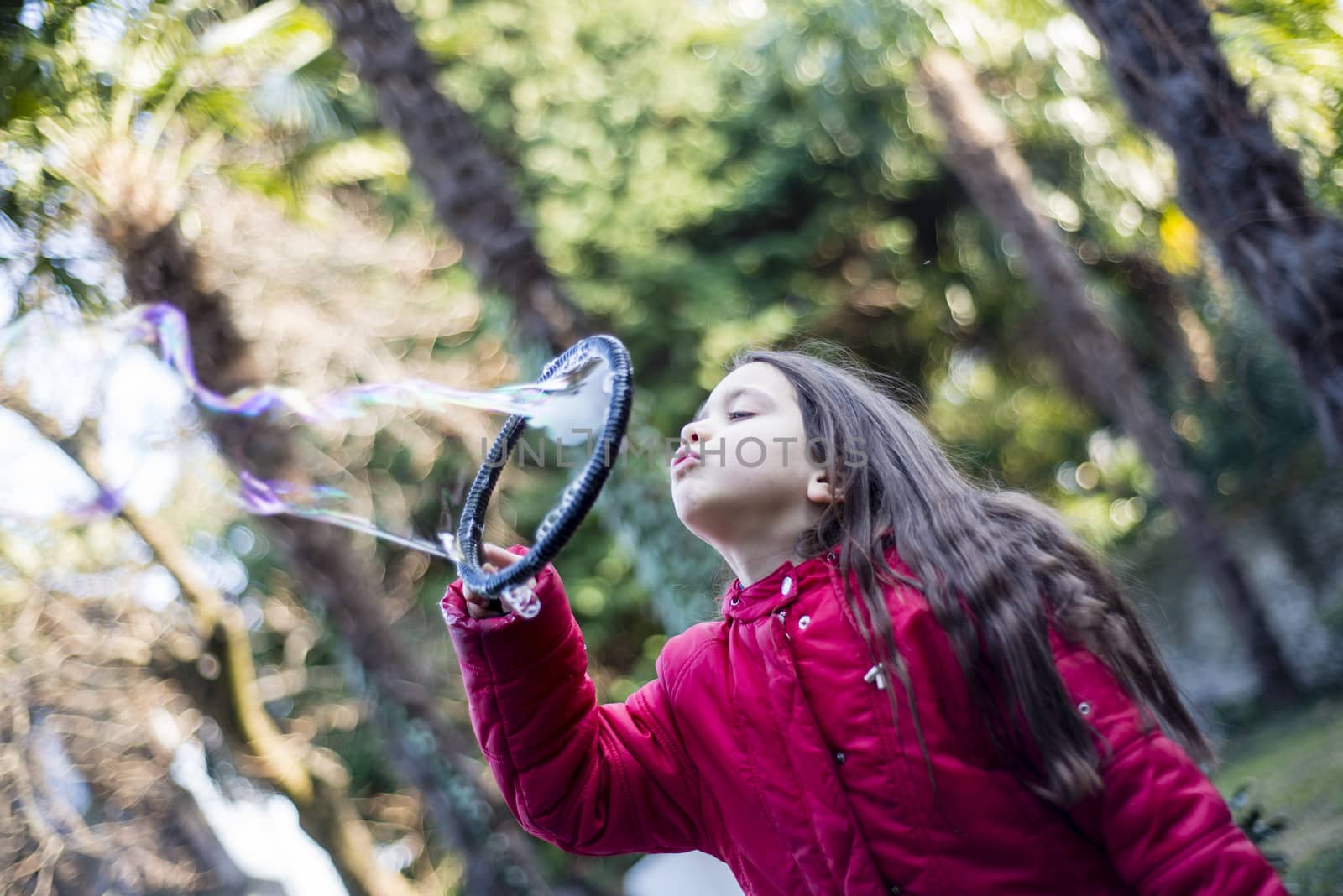 7 year old girl in outdoor in the garden in winter makes big soap bubbles